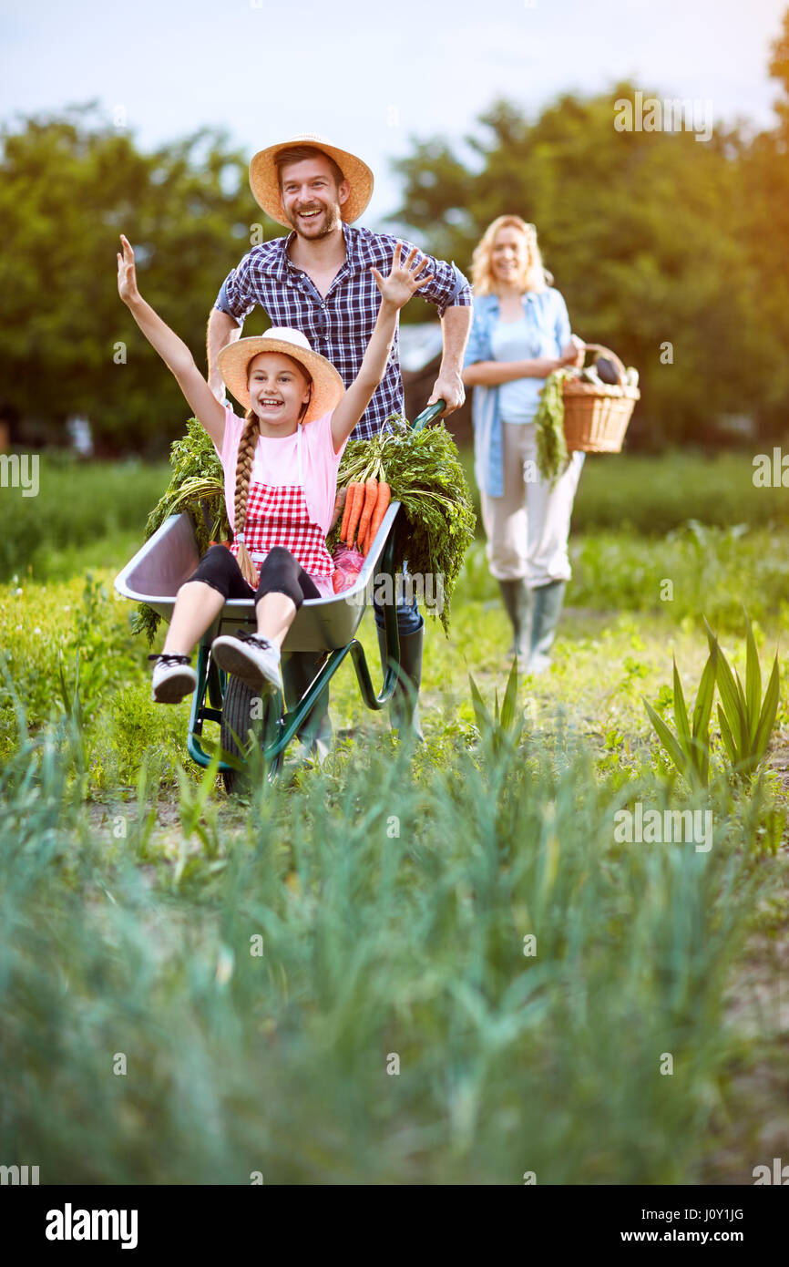Happy girl return from garden with father in wheelbarrow Stock Photo