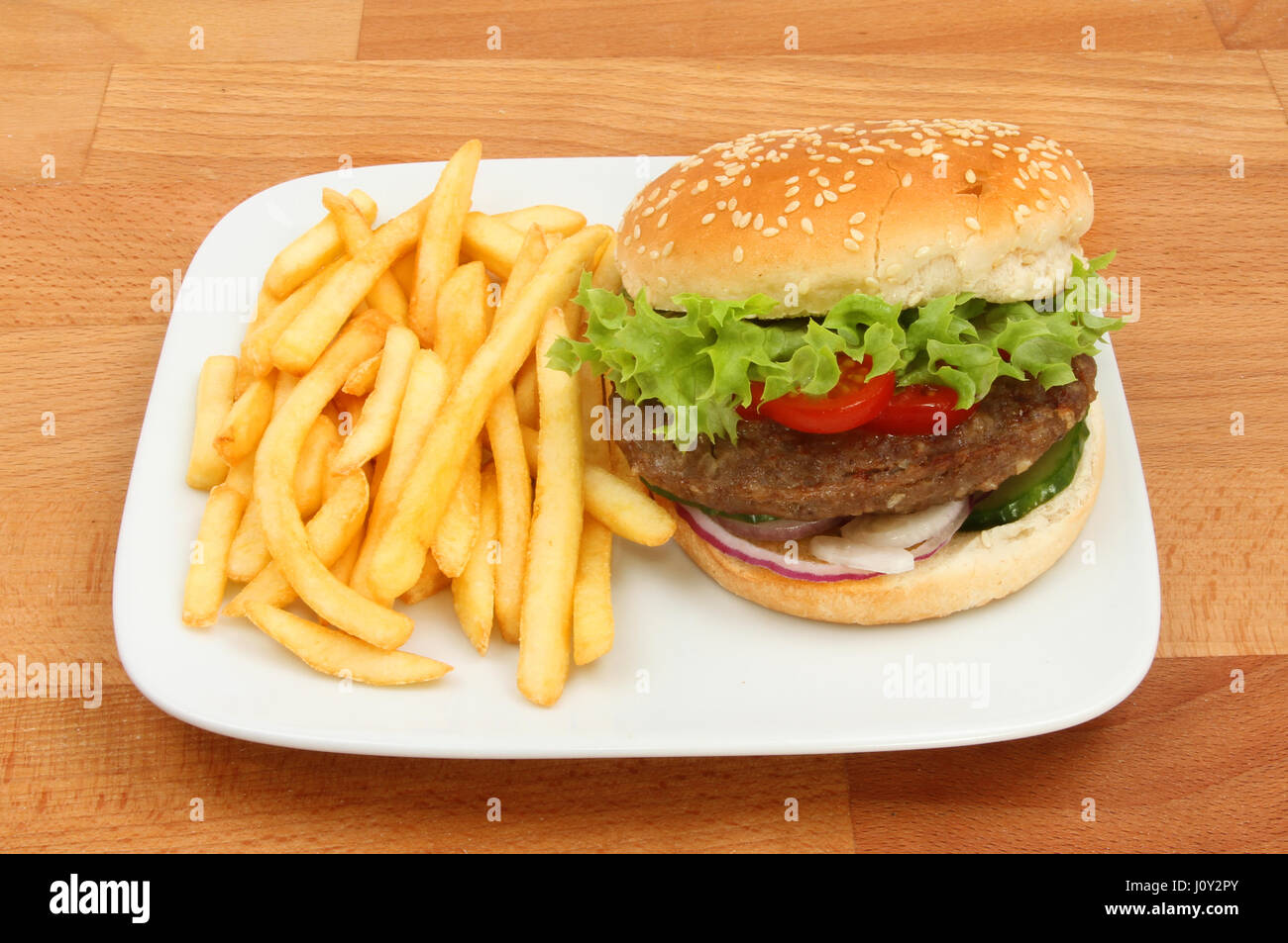 Beefburger with French fries on a plate on a wooden tabletop Stock Photo