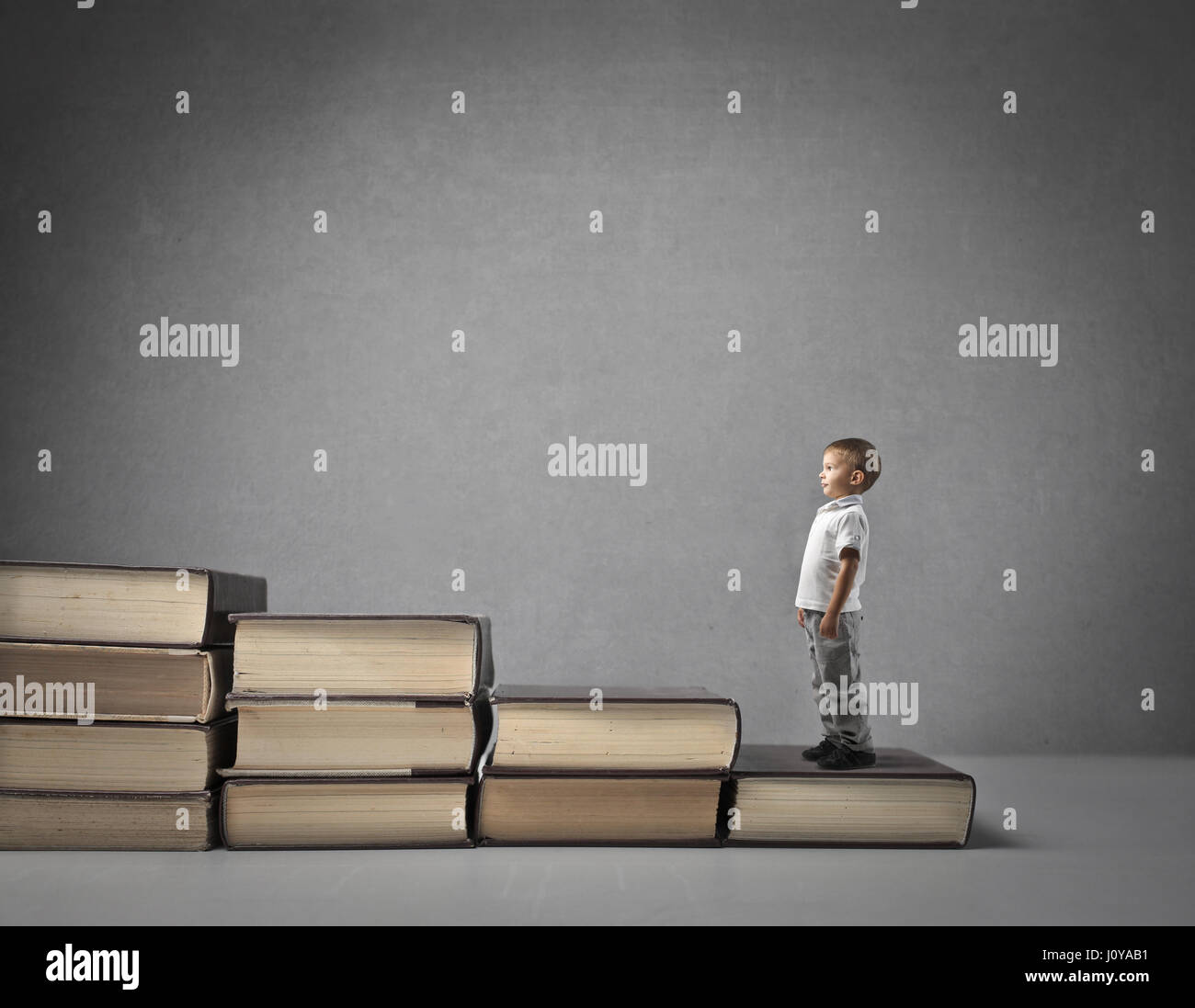 Little boy standing on stair made out of books Stock Photo