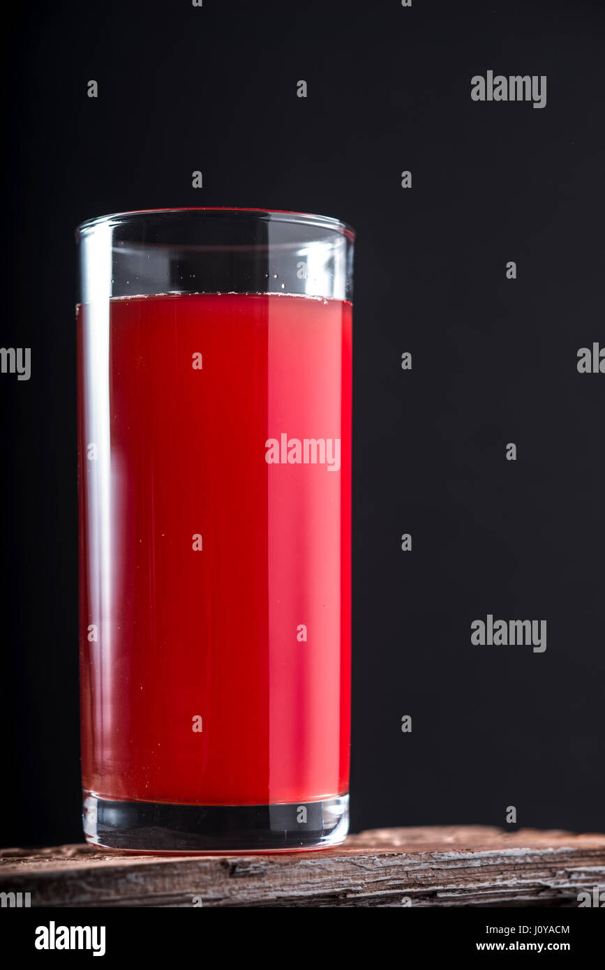 Cranberry drink in a tall glass on a black background vertical Stock Photo