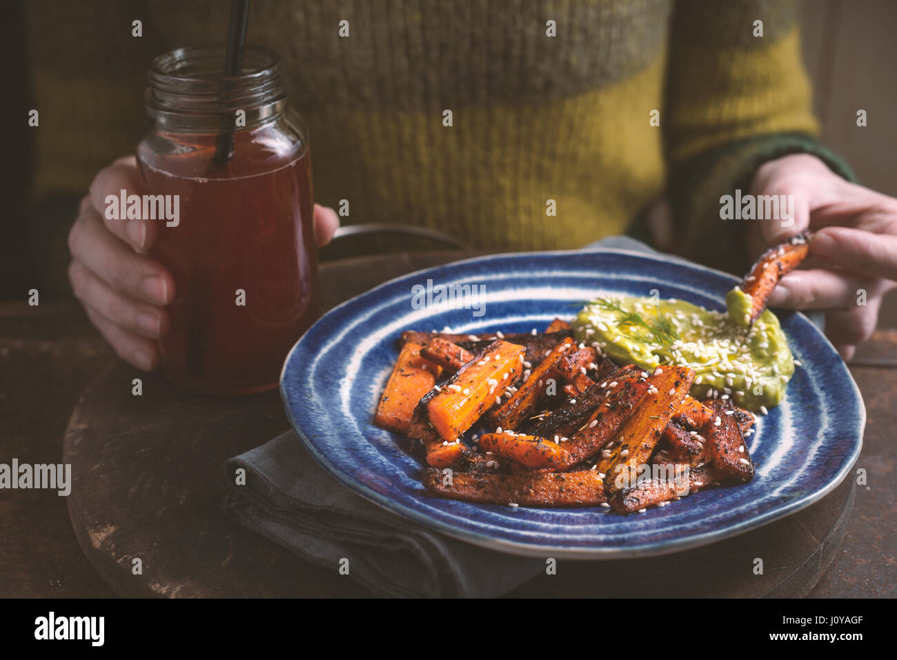 Woman eating roasted carrots with avocado sauce horizontal Stock Photo