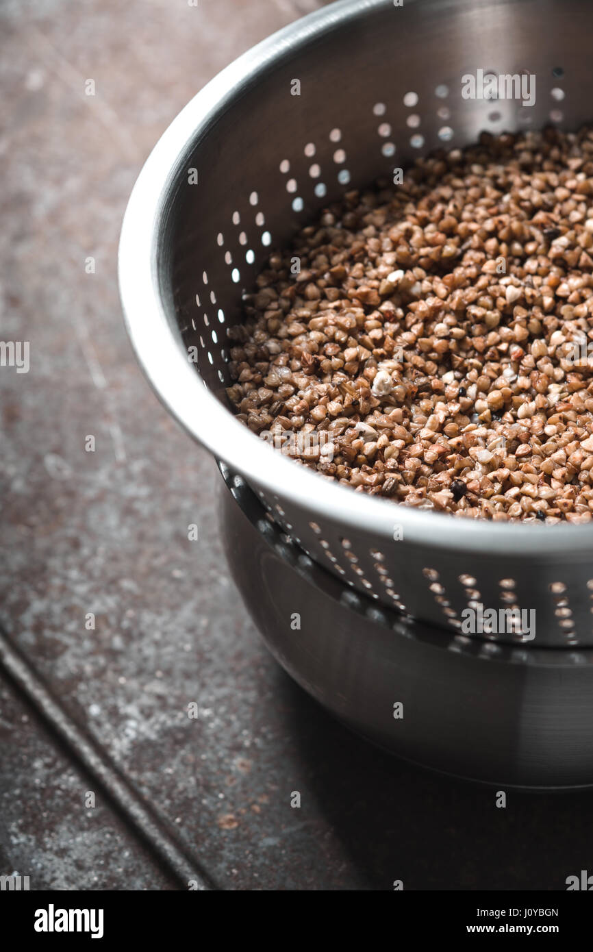 Buckwheat in the metal  colander  on the metal background vertical Stock Photo