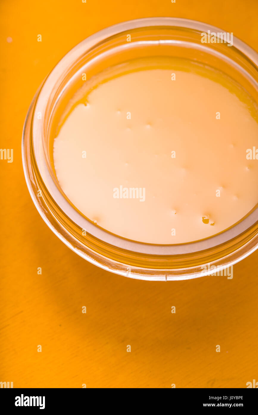 Thick honey in a glass bowl on a yellow table Stock Photo