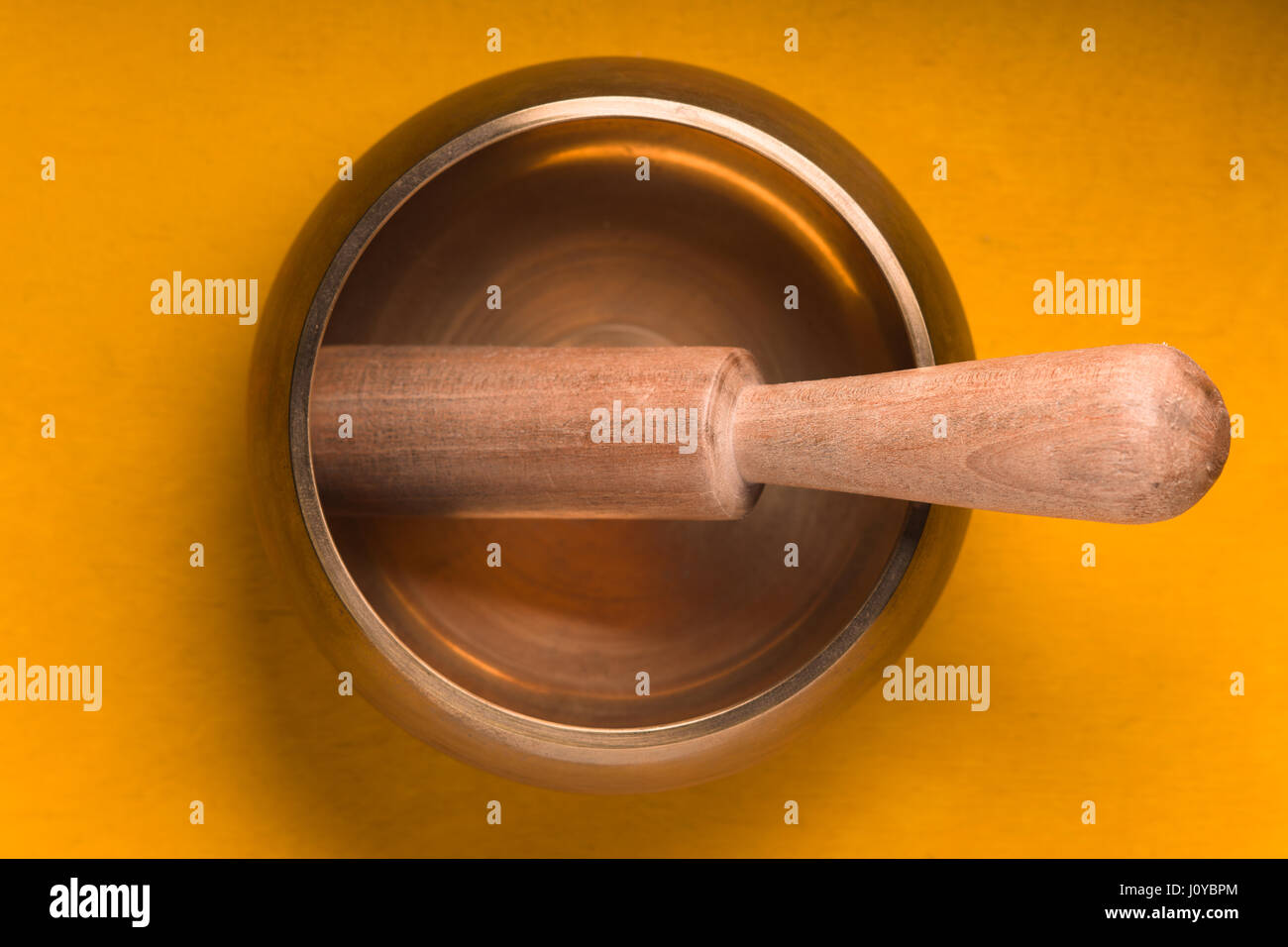 Metal bowl with a wooden stick on a yellow table Stock Photo