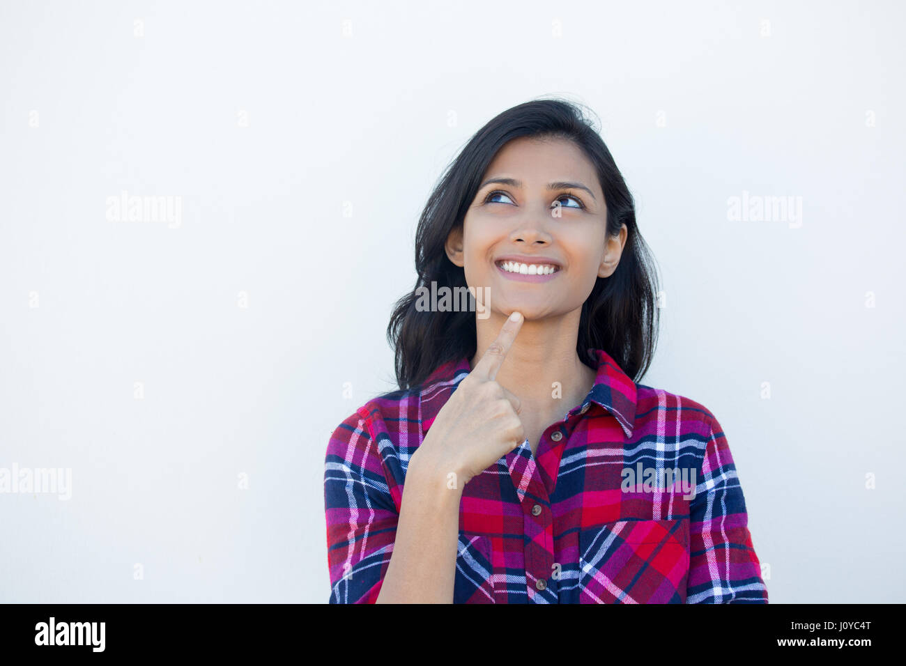 Closeup portrait, charming upbeat smiling joyful happy young woman looking upwards daydreaming something nice, isolated white wall background. Positiv Stock Photo