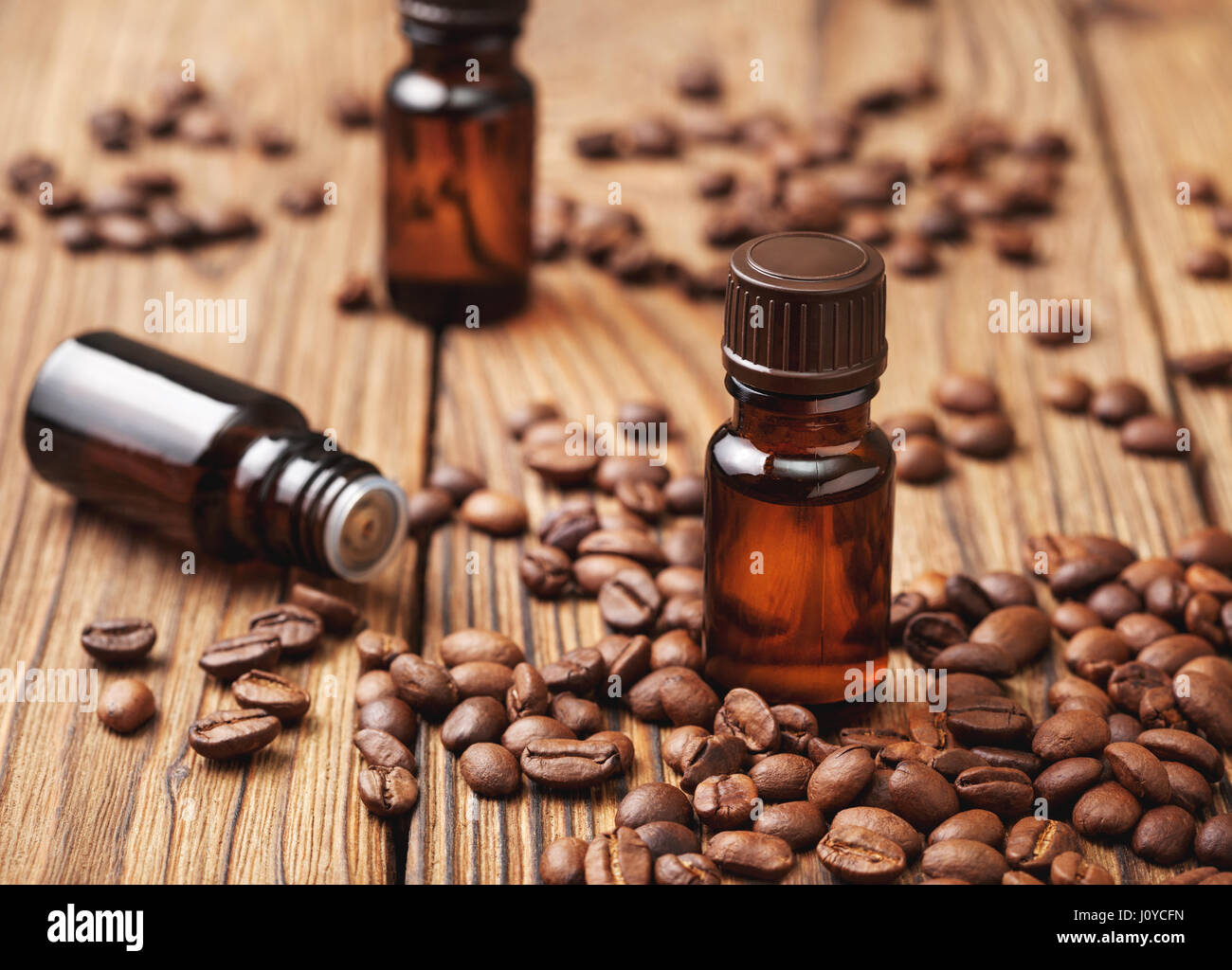Coffee essential oil in a glass bottle, coffee beans on wooden