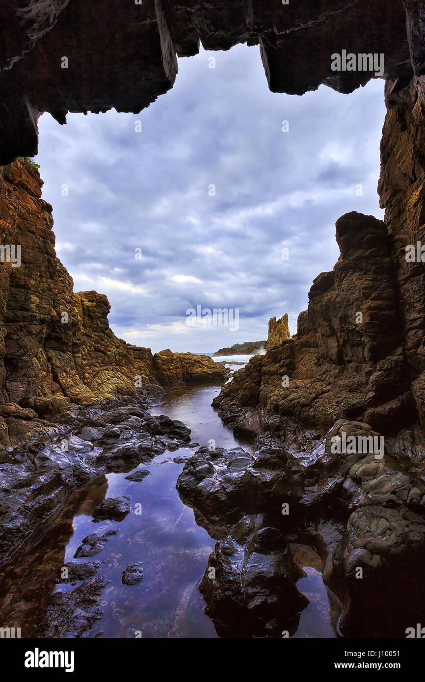 Rocky isolated grotto result of sea erosion at Cathedral rocks sandstone formation of Pacific coast in Australia near Kiama during sunset. Stock Photo