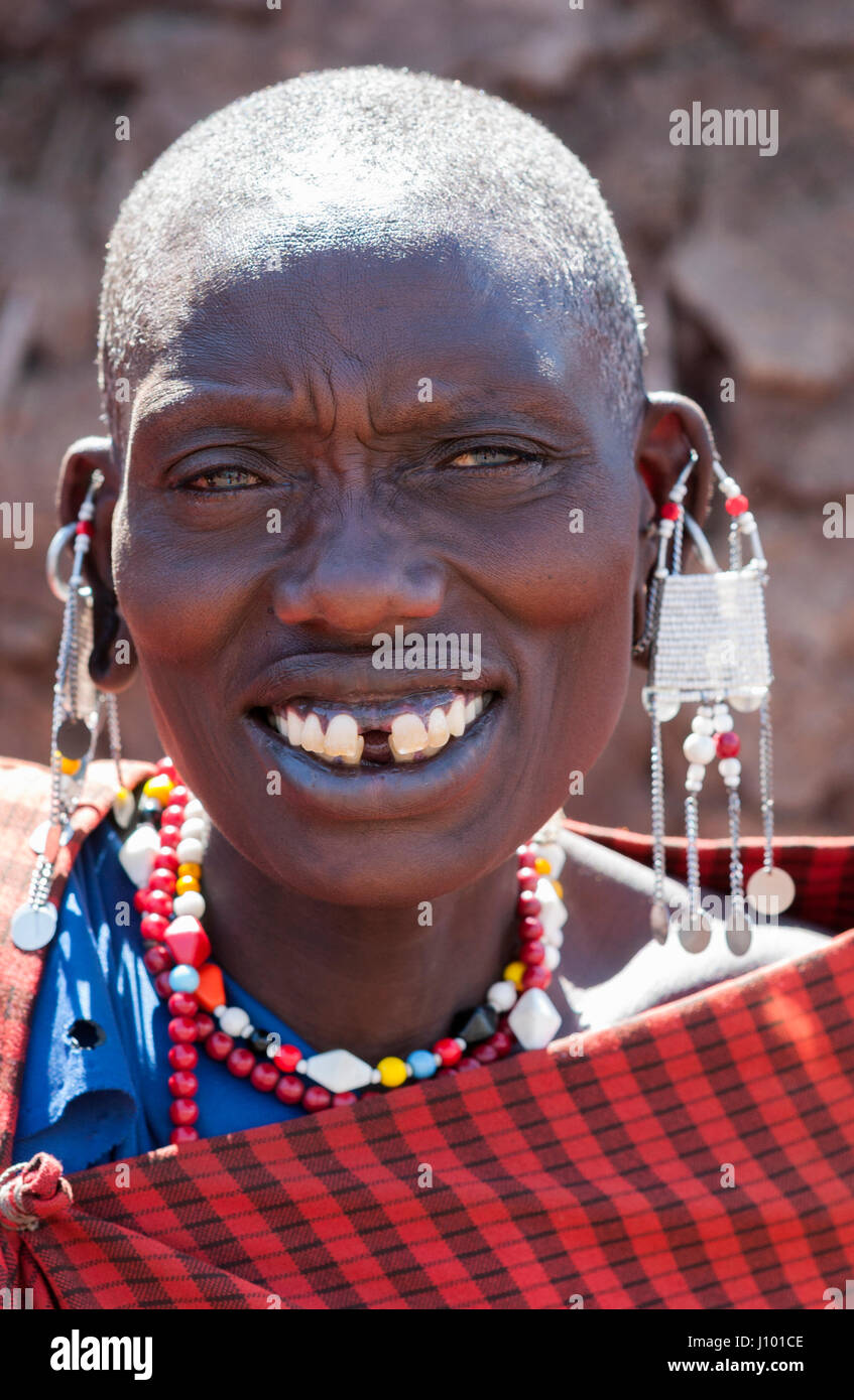 Beauty Portrait of a senior Maasai woman in her traditional beaded jewelry and ravishing smile in her traditional red garment. Stock Photo