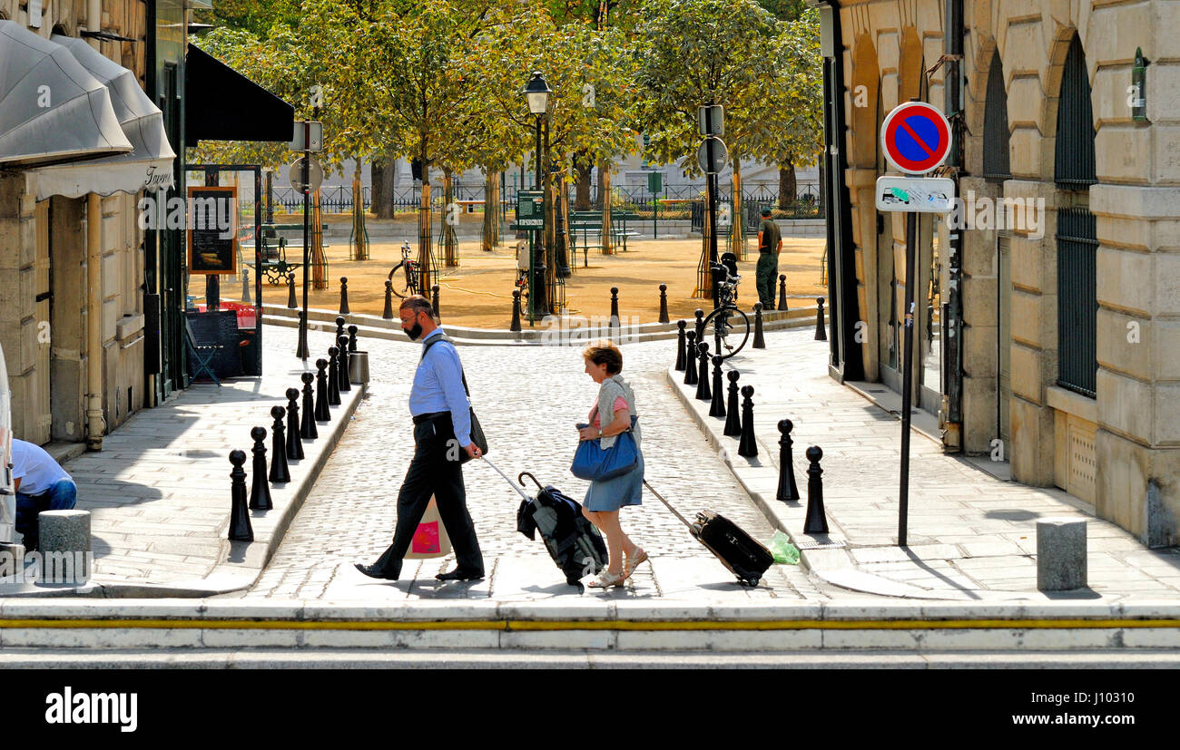 Paris, France. Isle de la Cite. Place Dauphine seen from Rue Henri-Robert. Couple wheeling luggage Stock Photo