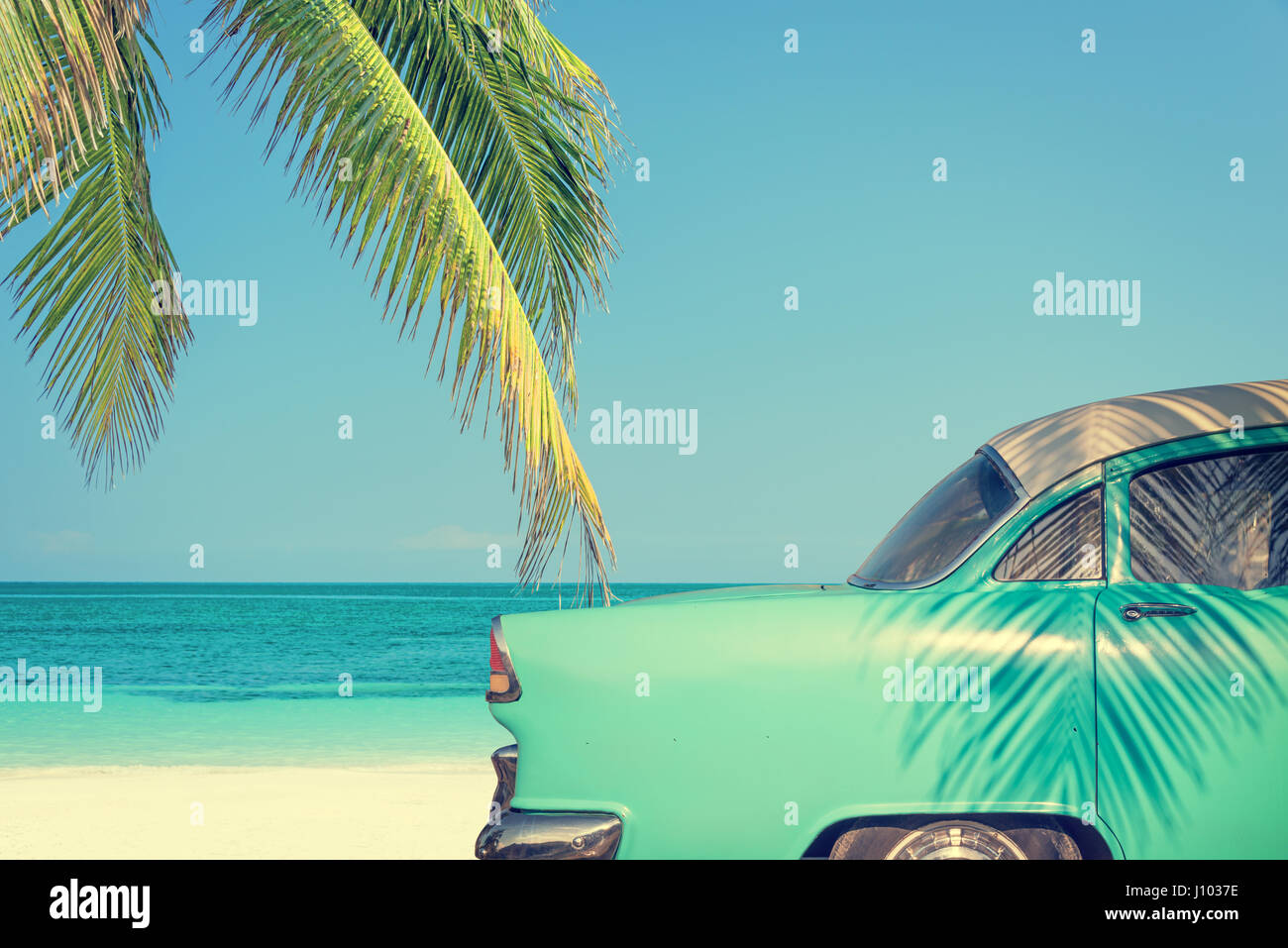 Classic car on a tropical beach with palm tree, vintage process Stock Photo