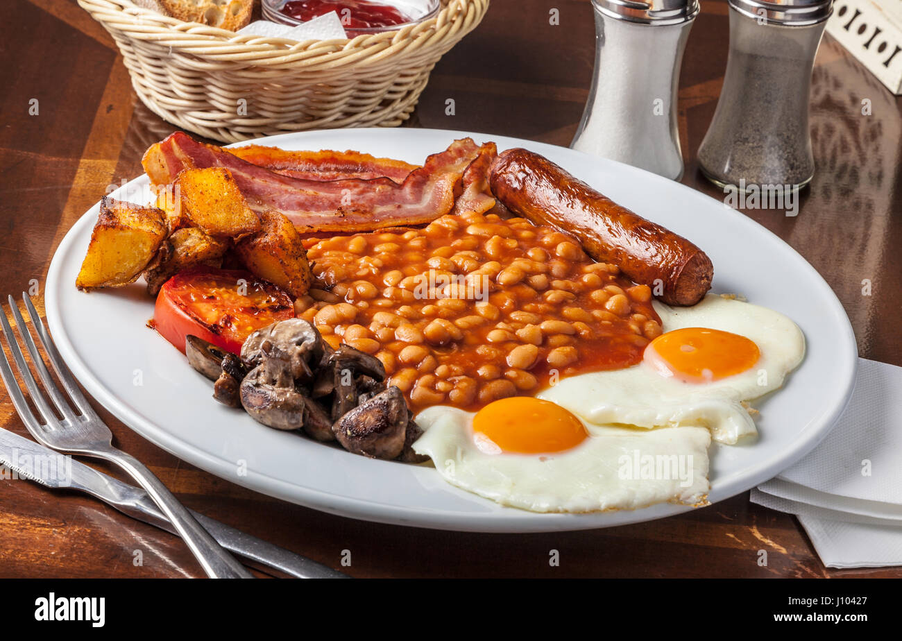 Brunch platter with sausage, eggs, bacon, beans, potatoes, tomato and  mushrooms Stock Photo - Alamy