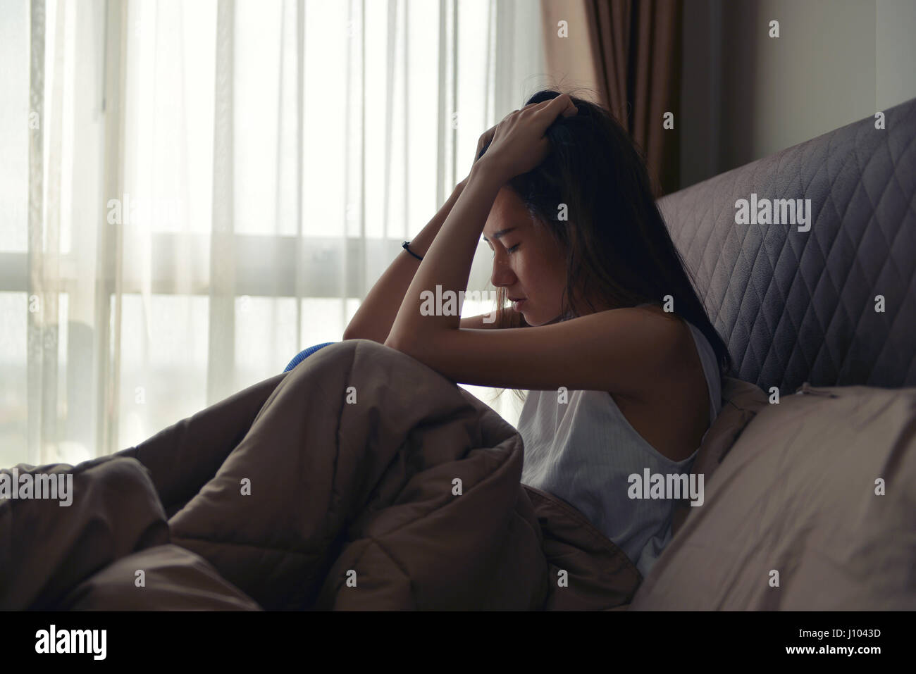 Asian Woman Suffering From Depression Sitting On Bed Stock Photo