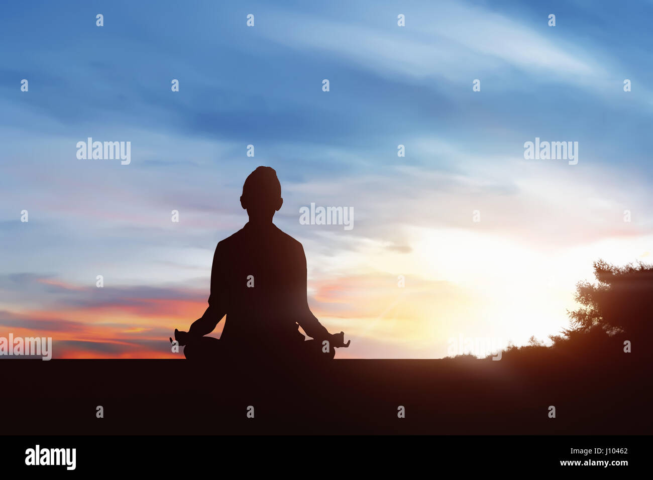 Silhouette of young woman practicing yoga in outdoor at sunrise Stock Photo
