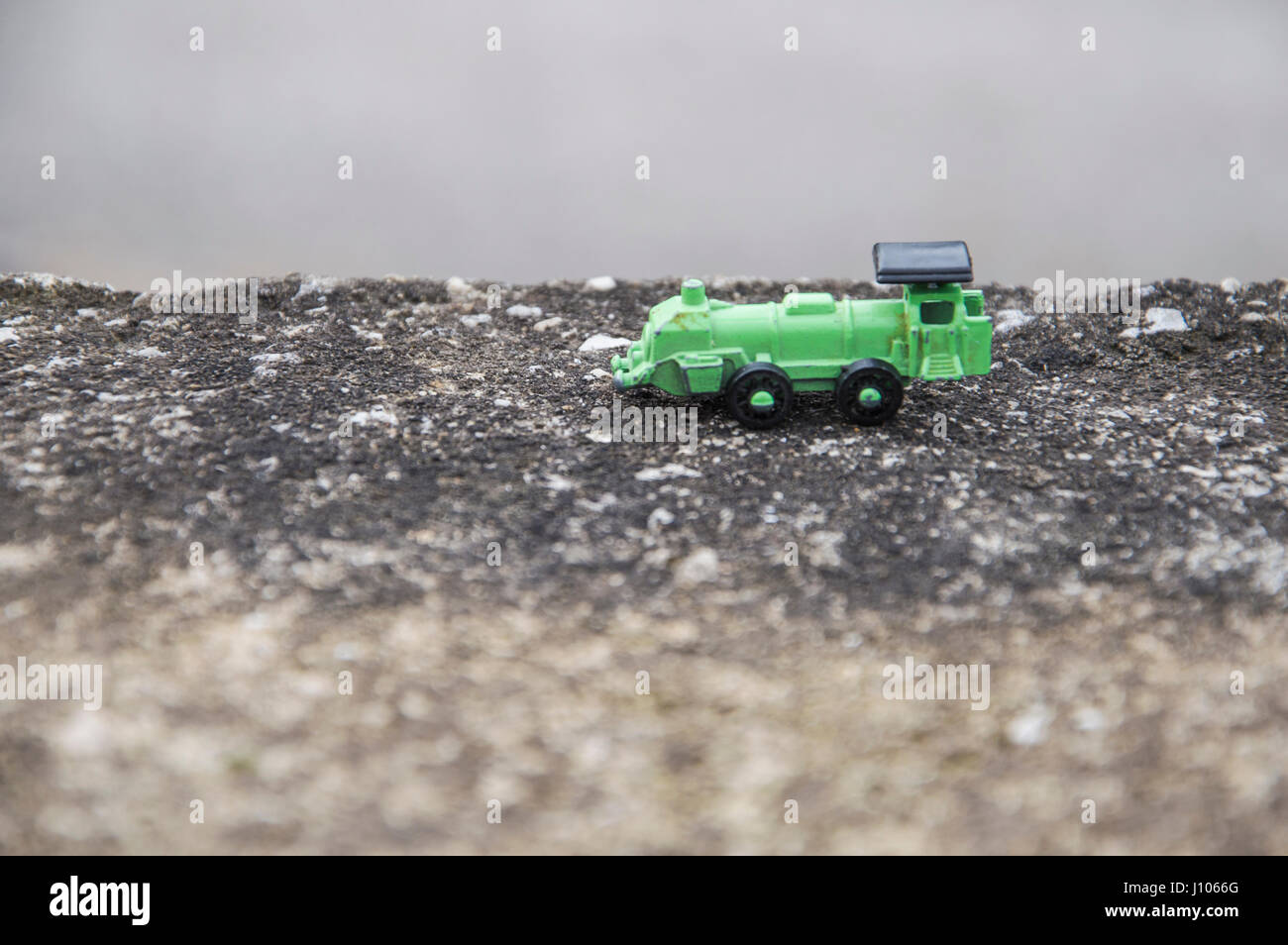 Green steel toy train in an asphalt background, conceptual photo Stock