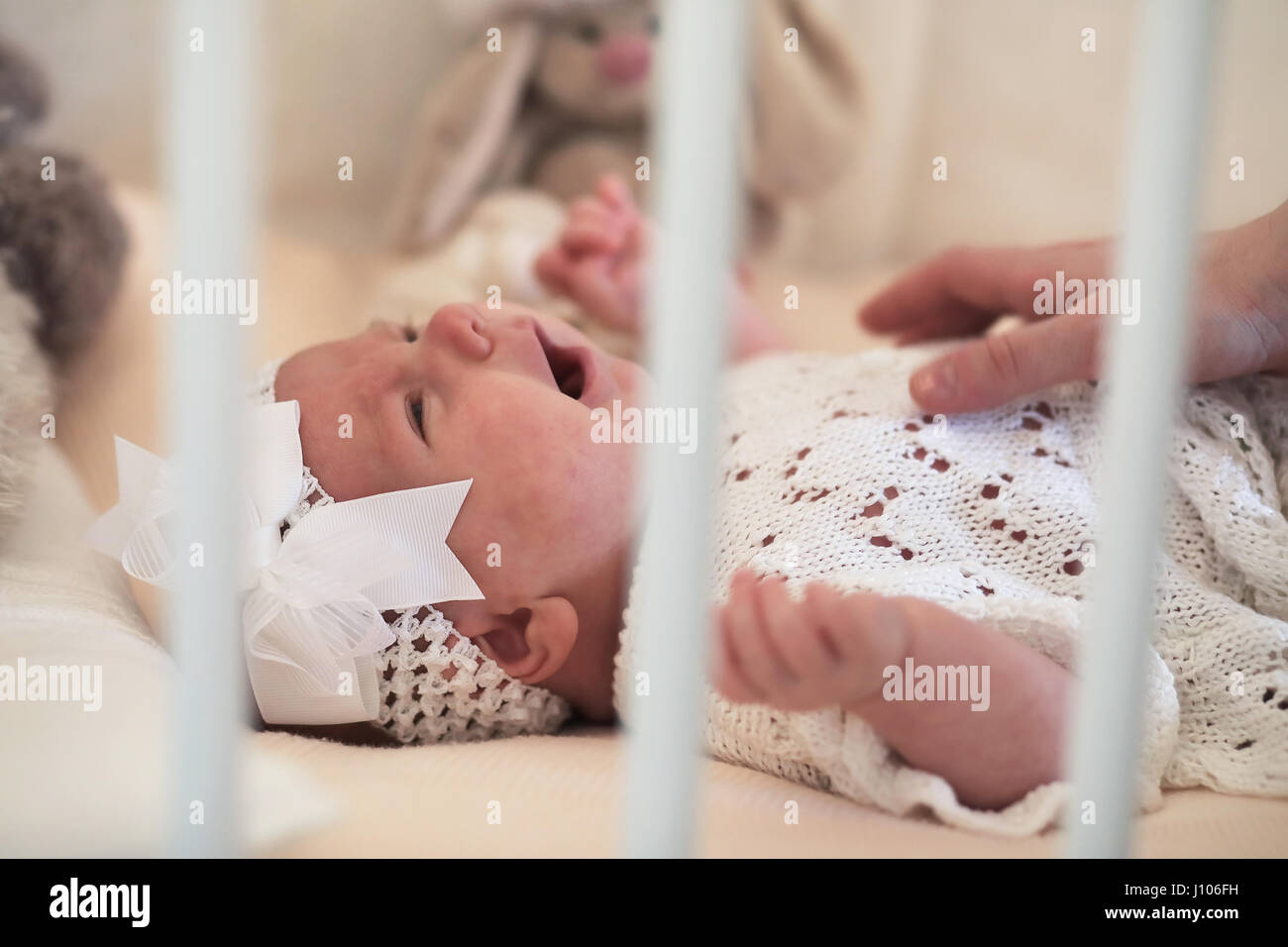 Cute newborn baby lies in the crib and looking mother Stock Photo