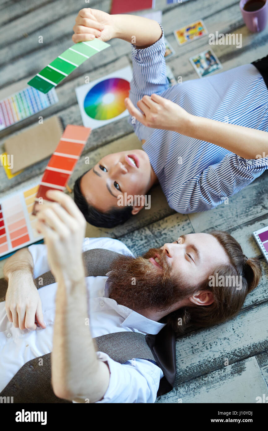 Young man and woman lying on the floor and discussing color swatches ...