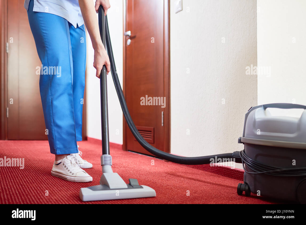 Housekeeper cleaning carpet with vacuum-cleaner Stock Photo