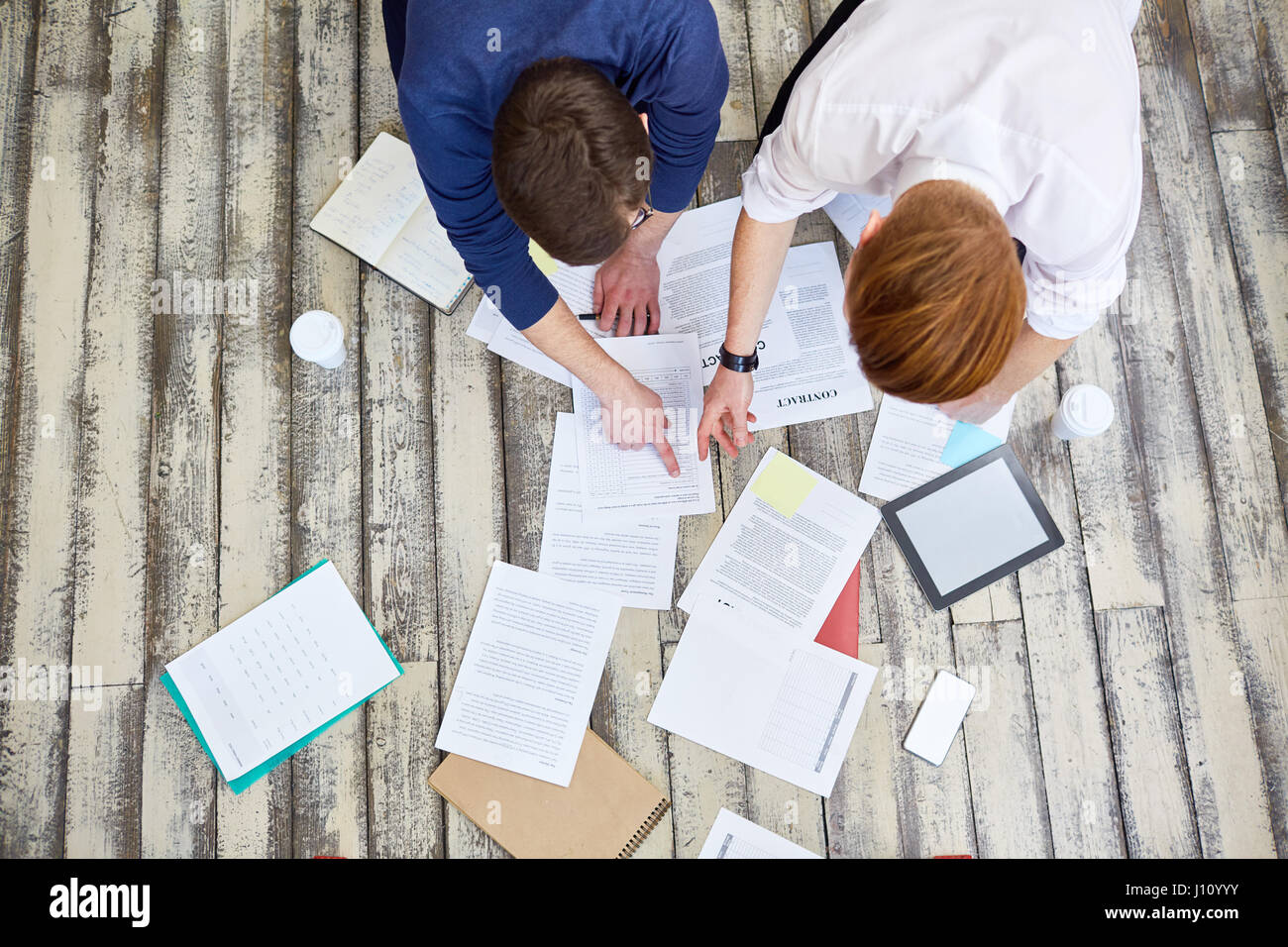 Above view of two business people sorting documents laying papers out of floor in office and discussing work Stock Photo