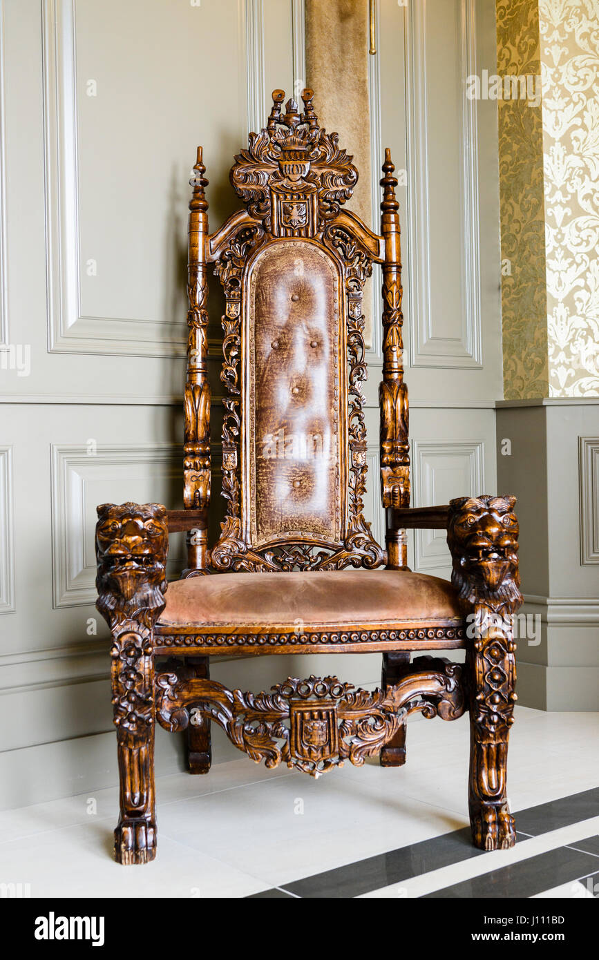 An old, intricately carved oak wood chair with leather upholstering in a stately home. Stock Photo