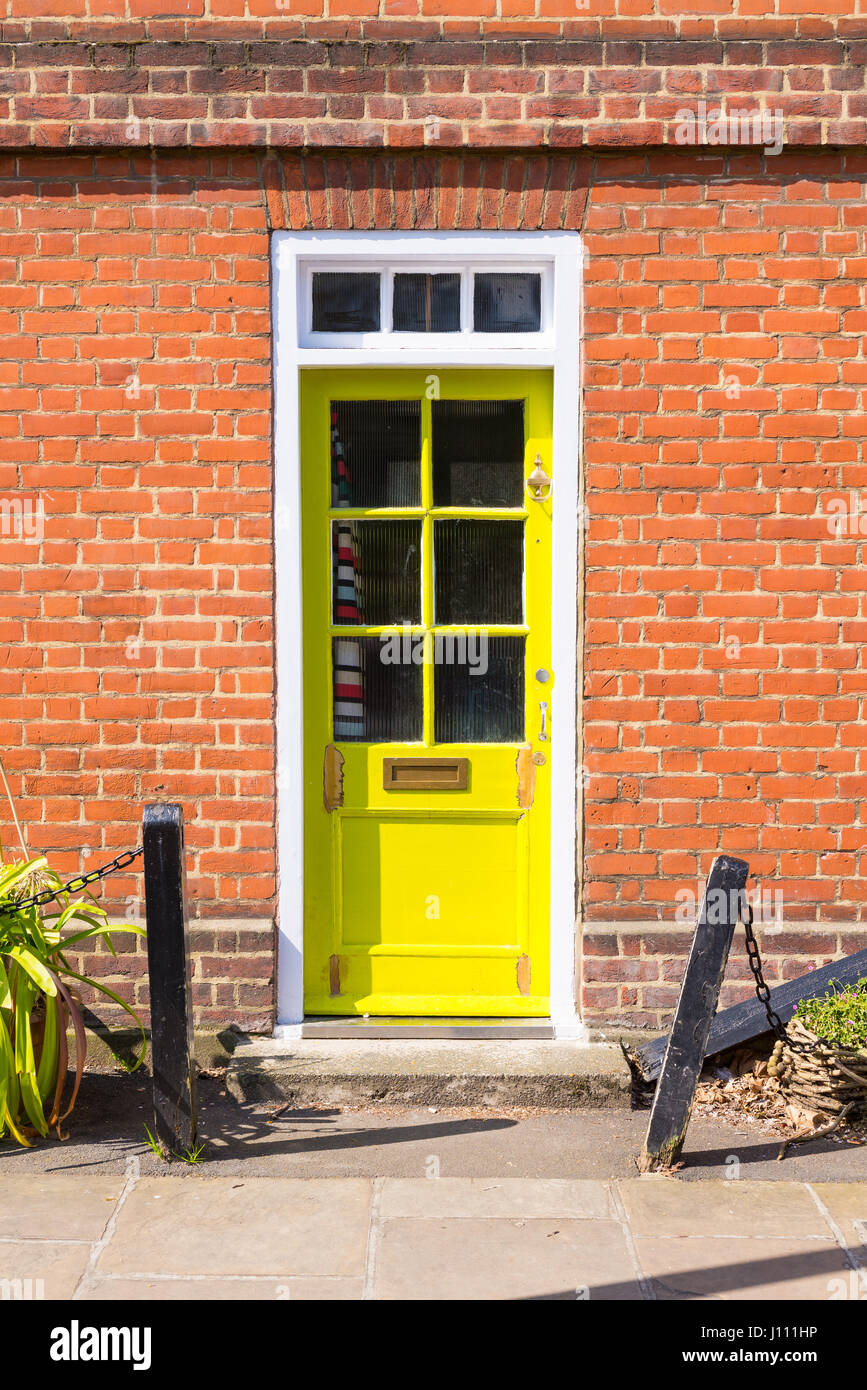Bright yellow Victorian British front door on a red brick wall Stock