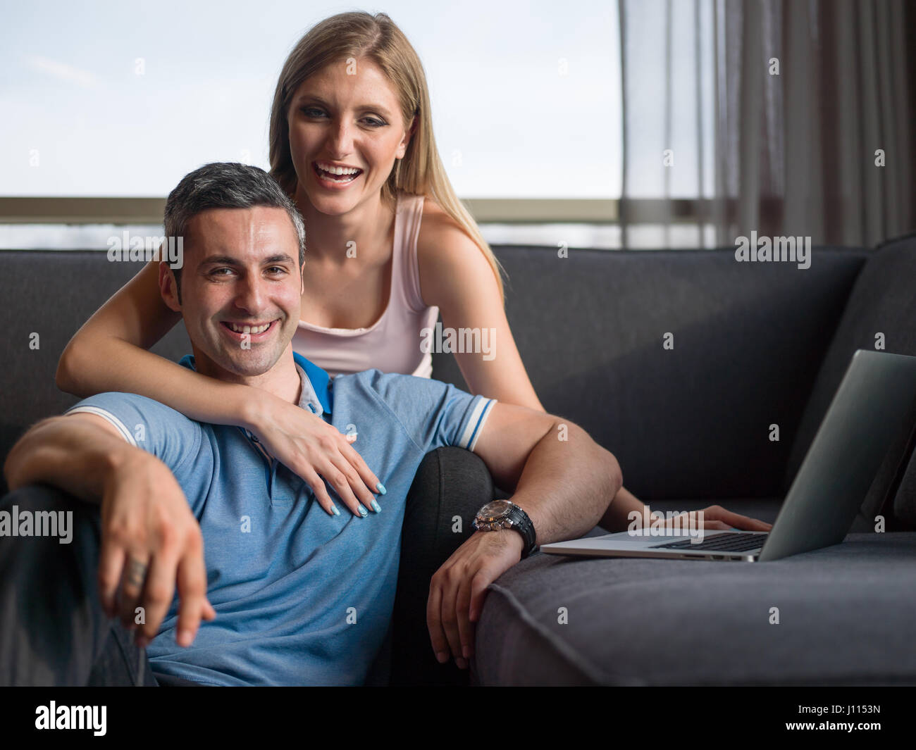 Attractive couple using a laptop in the living room Stock Photo - Alamy