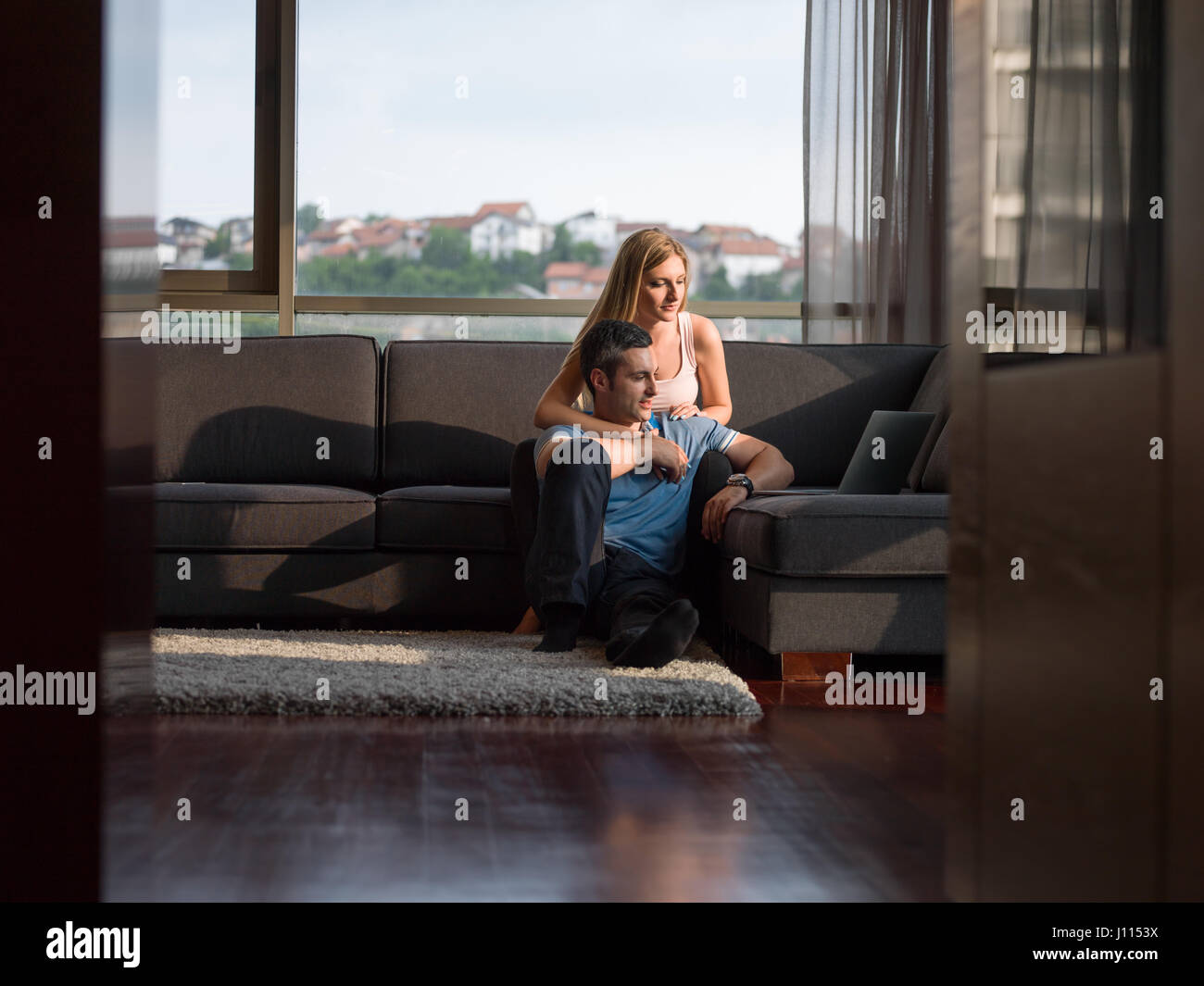 Attractive couple using a laptop in the living room Stock Photo - Alamy
