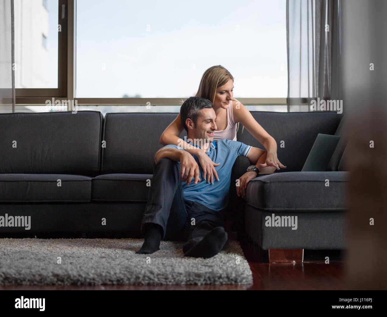 Attractive couple using a laptop in the living room Stock Photo - Alamy