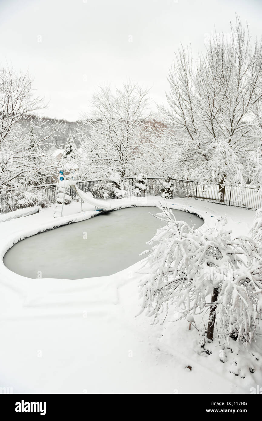 Backyard swimming pool in winter, after heavy snow fall, storm, covered with snow and ice, London, Ontario, Canada. Stock Photo