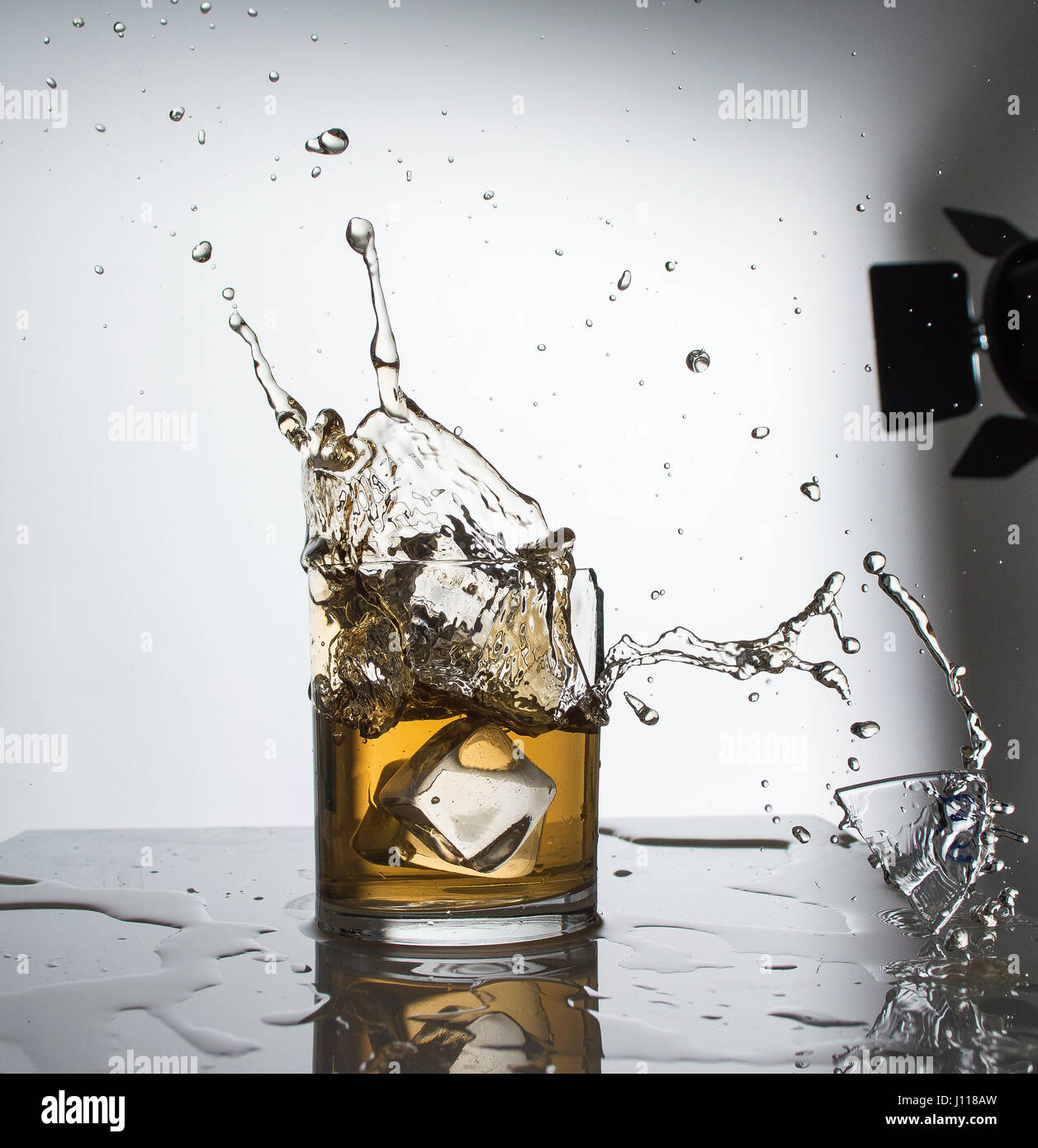 Splashing acrylic ice-cubes into a whiskey glass. Stock Photo