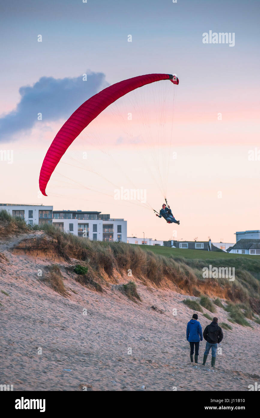 Paraglider; UK; Paragliding; Flying; Evening; People watching; Flying low; Fistral Beach; Cornwall; Evening; Physical activity; Skill Stock Photo