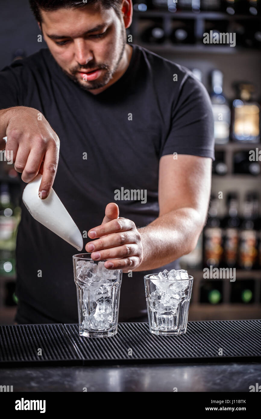 Glass filled with ice cubes. Bartender preparing cocktail Stock Photo