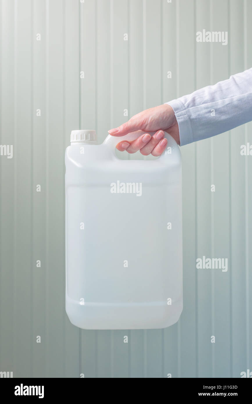 White unlabeled plastic 5 liters tank canister in female hand, chemistry and chemical liquids mock-up container Stock Photo