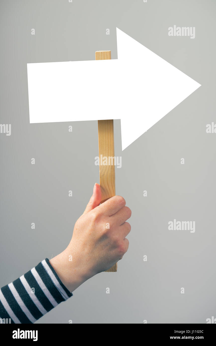 Woman holding guiding direction arrow sign in hand, concept of guidance and decision making Stock Photo