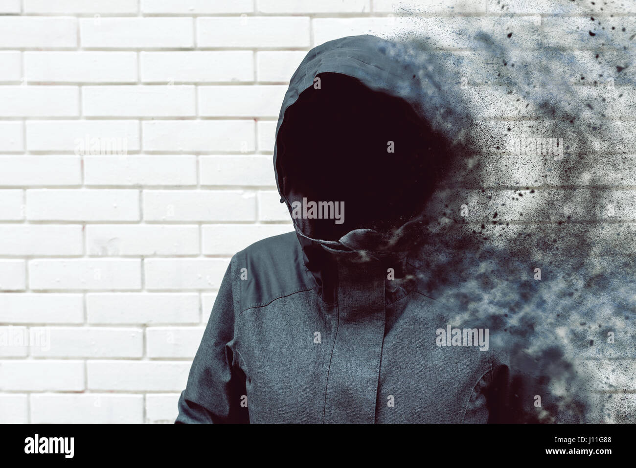 Thinking mind blowing thoughts, faceless hooded person against white brick wall Stock Photo
