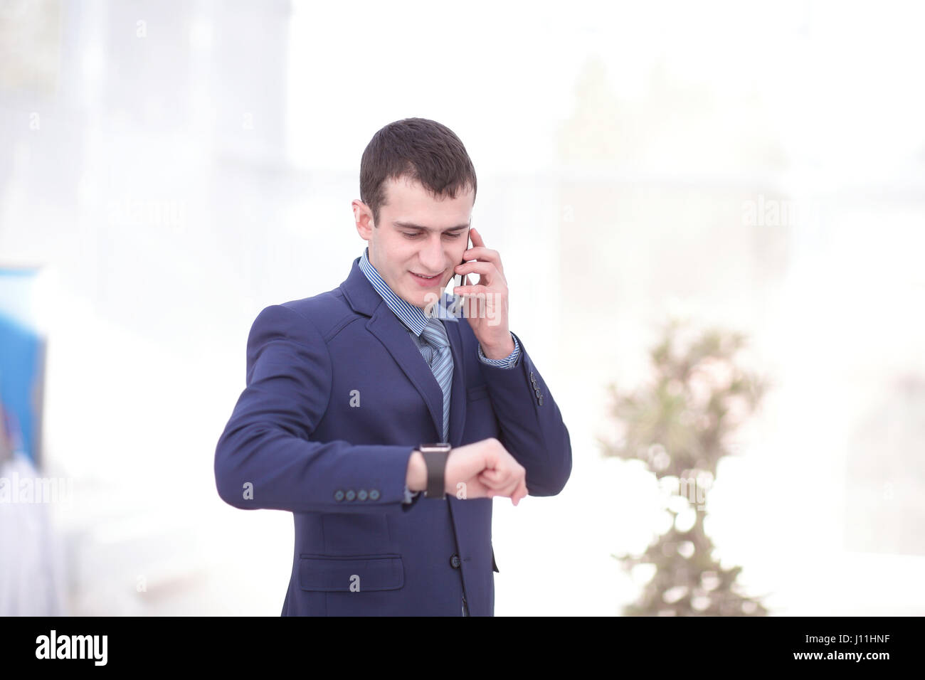 Good business talk. Handsome young man in formalwear talking on the phone and smiling while sitting at the office desk Stock Photo