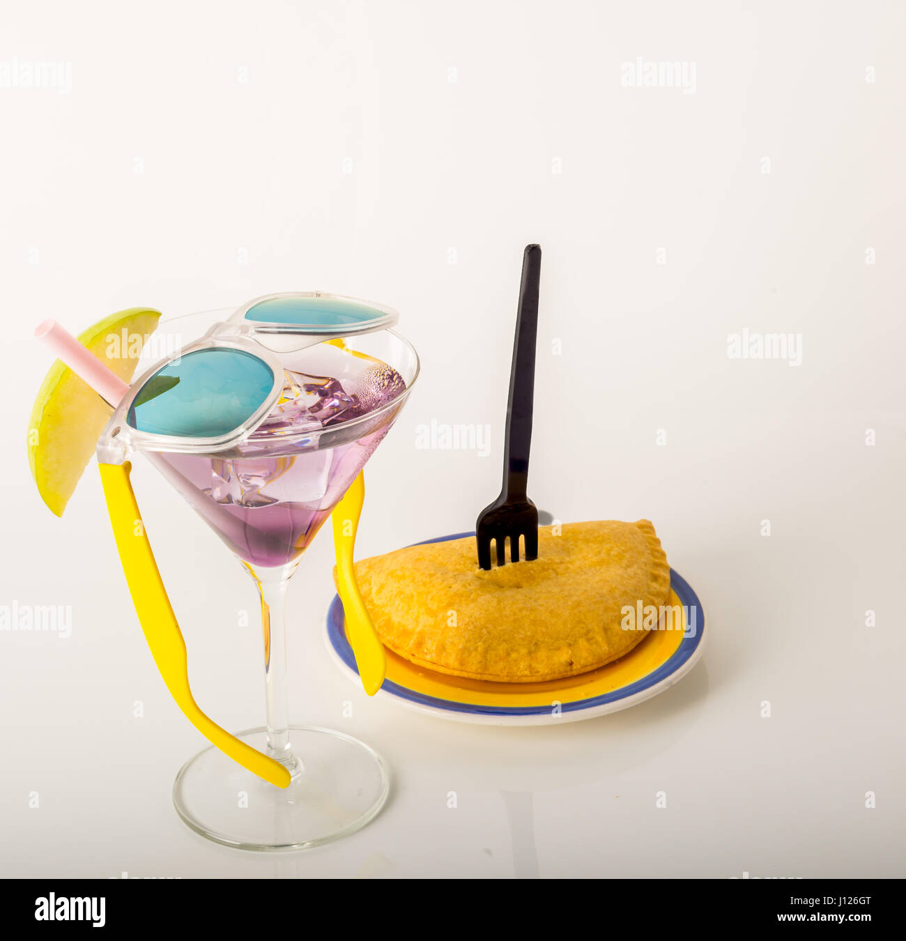 drink decorated with fruit, martini glass, drink staw and ice cubes