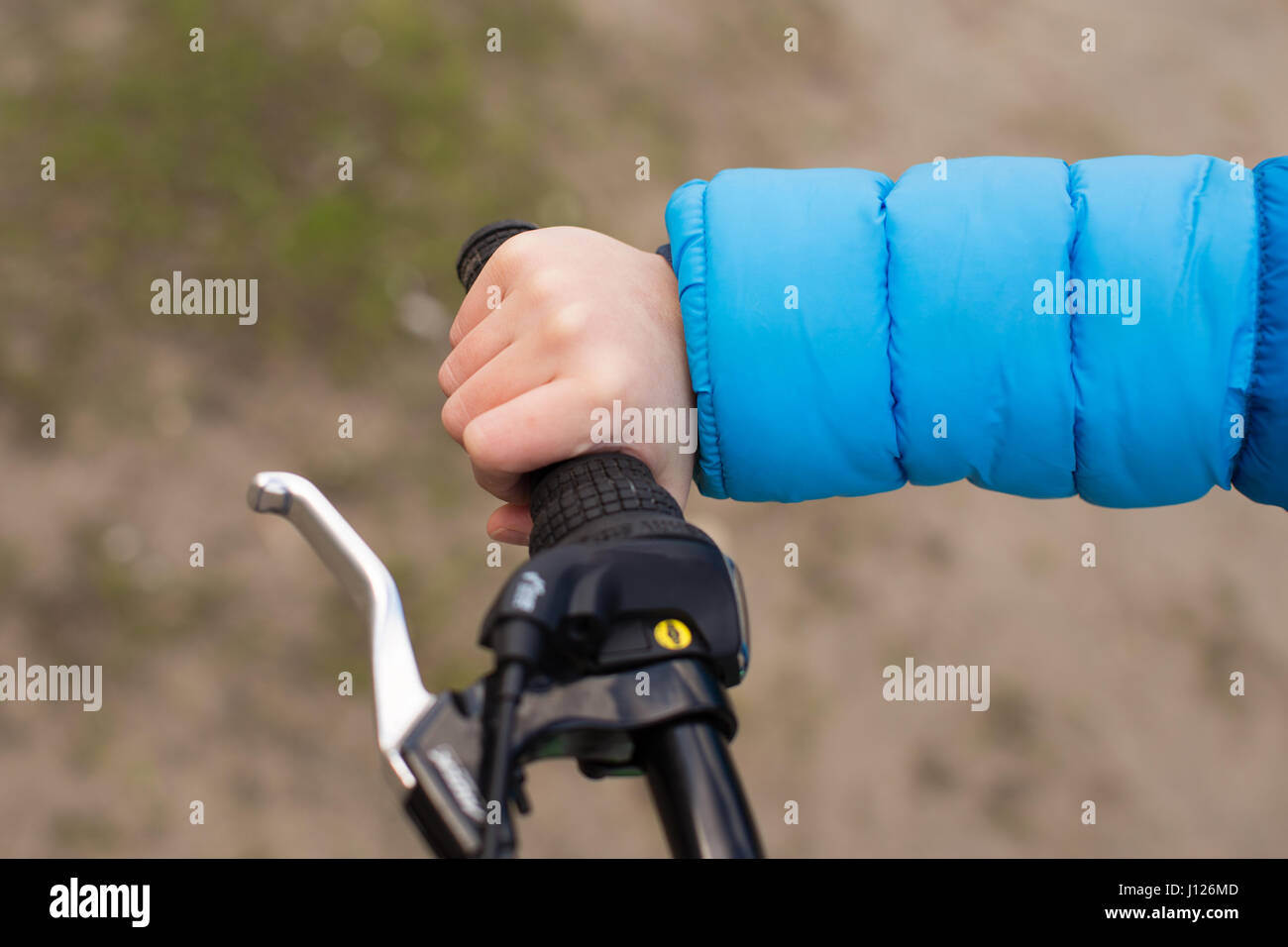 The right hand of the boy holds the bicycle handle firmly Stock Photo