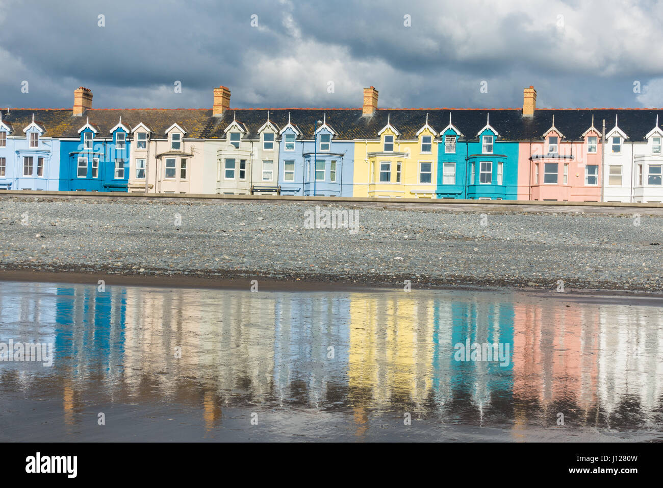 A row of colourful houses at y Borth, on Cardigan Bay, reflected on the wet beach Stock Photo