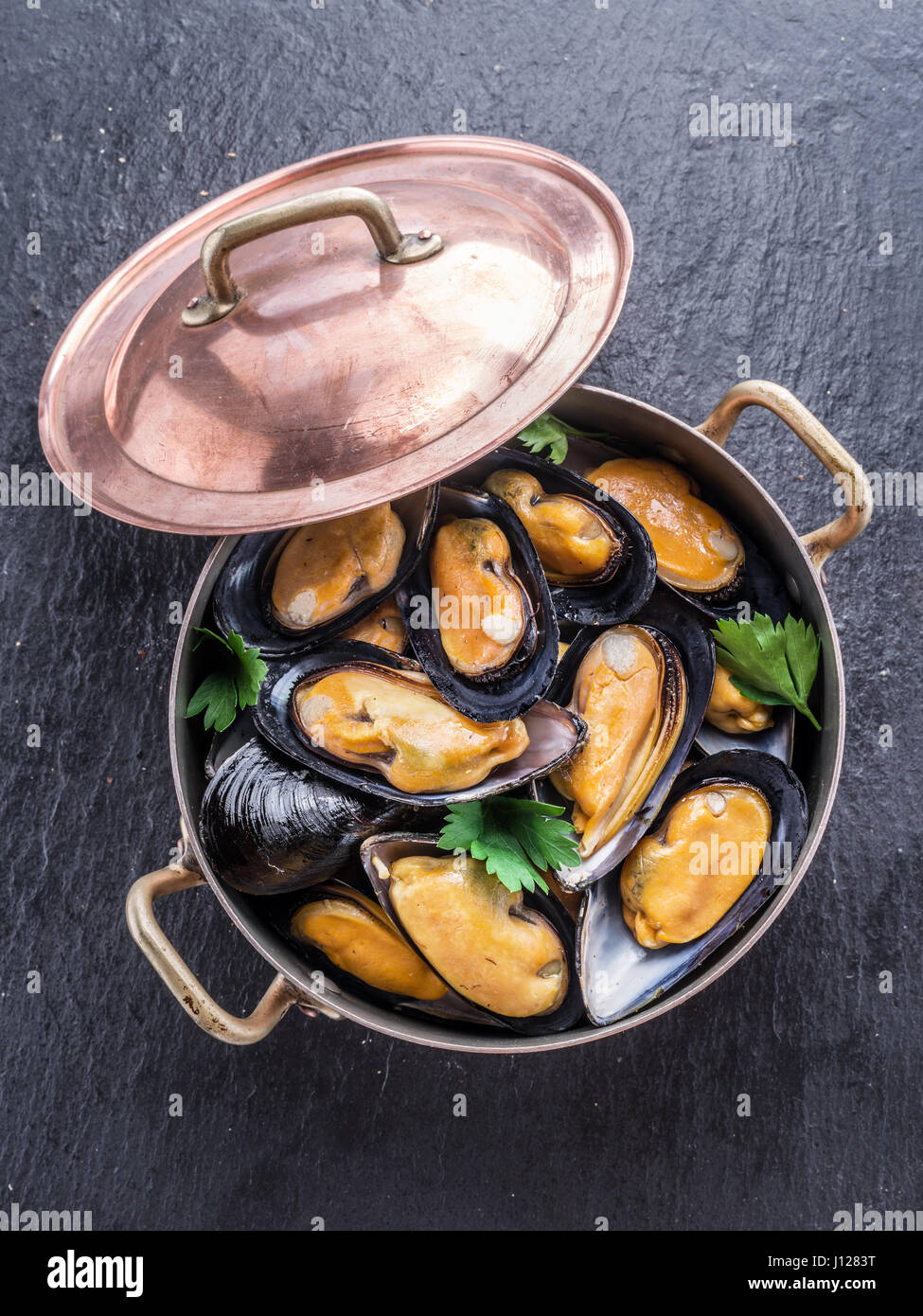 Boiled mussels in copper pan on the graphite background. Stock Photo