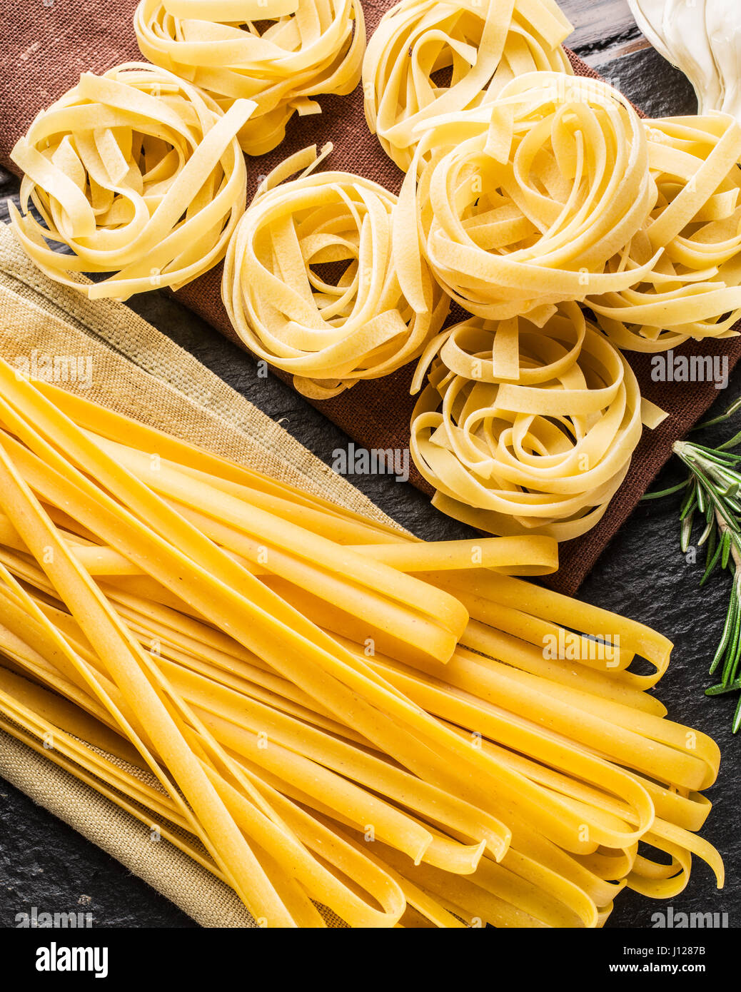 Pasta ingredients. Cherry-tomatoes, spaghetti pasta, rosemary and spices on a graphite board. Stock Photo