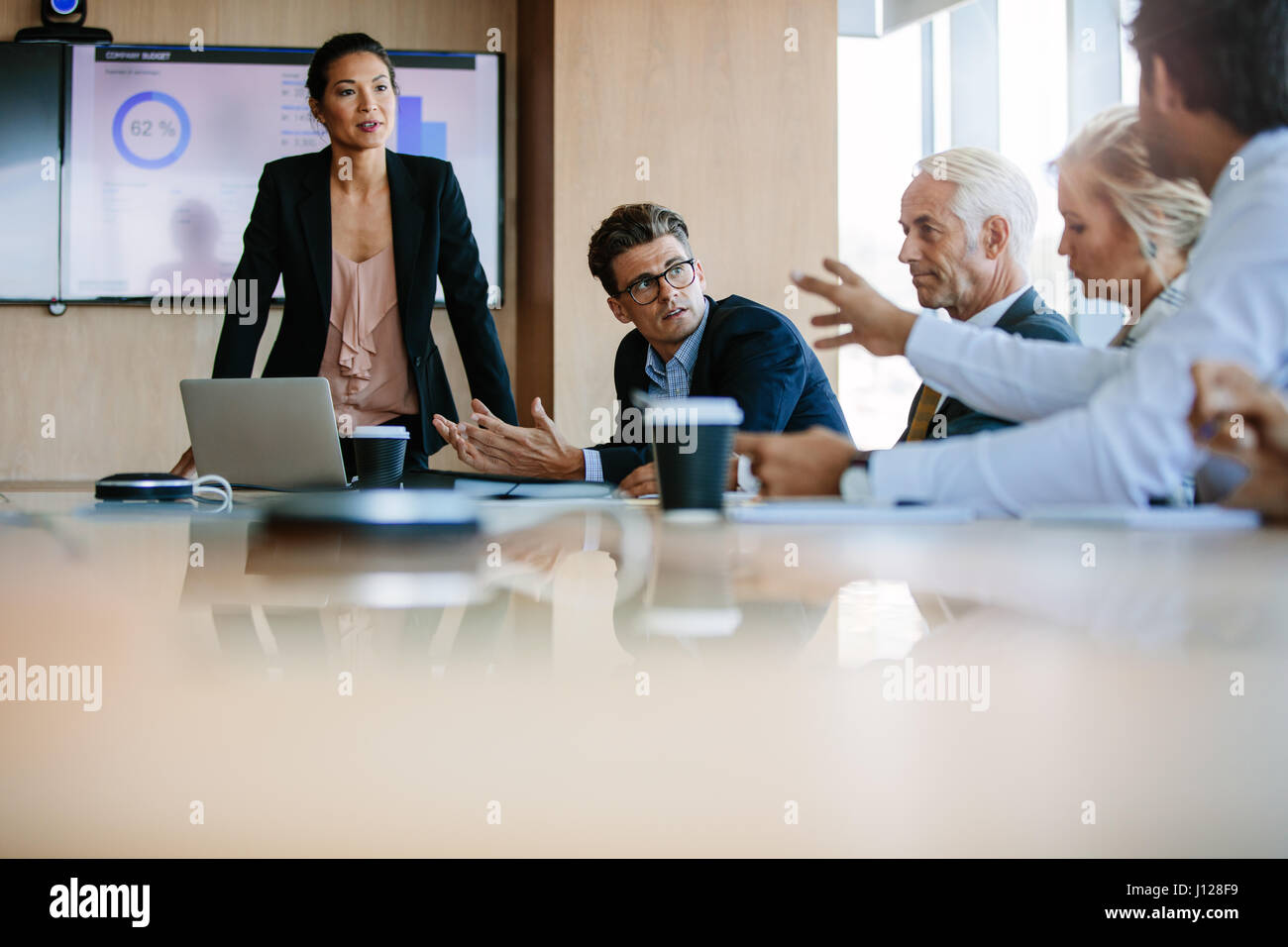 Team of business people sitting together in discussion around conference  table. Diverse business group having a meeting in boardroom Stock Photo -  Alamy
