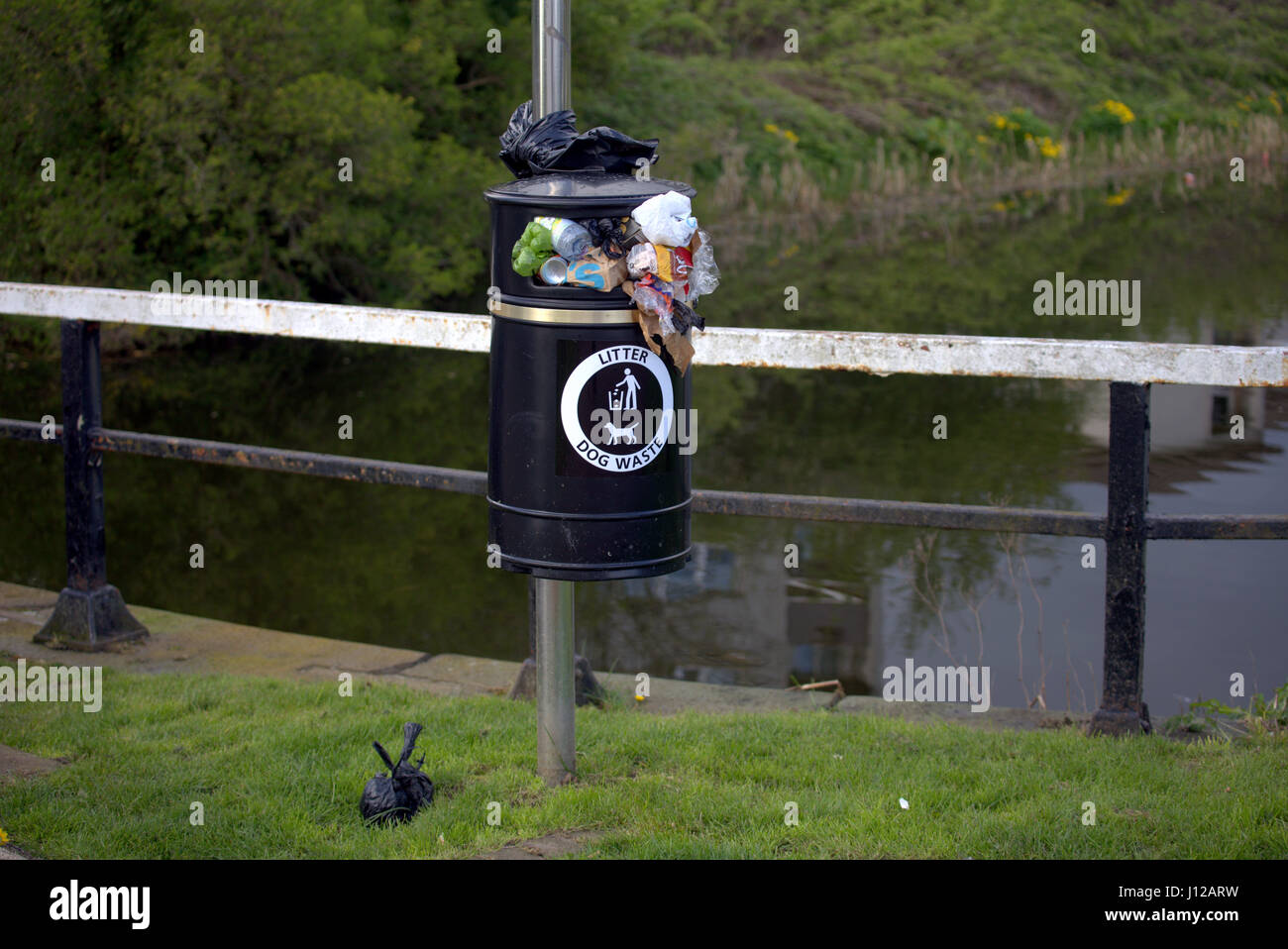 canal side overflowing litter bin dog poo bin Stock Photo