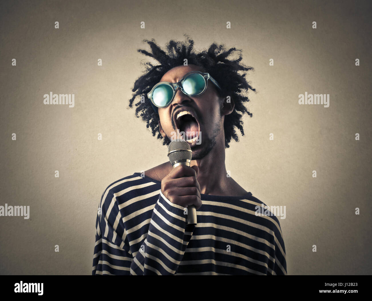 young black man singing in microphone Stock Photo