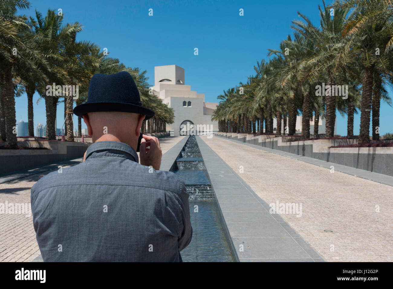 Western Tourist taking an iPhone photo of the Museum of Islamic Art, Doha, Qatar Stock Photo