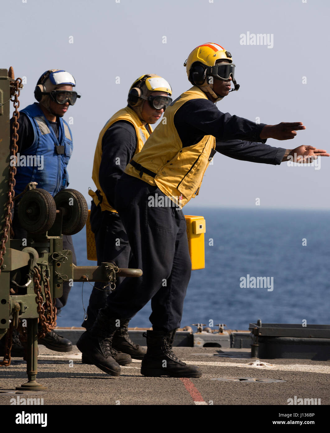 GULF OF ADEN (April 4, 2017) — U.S. Navy Seaman Aaron Brooks signals Sailors to chain down an MH-60S Sea Hawk assigned to the Desert Hawks of Helicopter Sea Combat Squadron (HSC) 26, after it lands on the flight deck of the amphibious dock landing ship USS Carter Hall (LSD 50) during flight operations April.  Carter Hall, part of the Bataan Amphibious Ready Group, is deployed to the U.S. 5th Fleet area of operations in support of maritime security operations designed to reassure allies and partners and preserve the freedom of navigation and the free flow of commerce in the region . (U.S. Marin Stock Photo