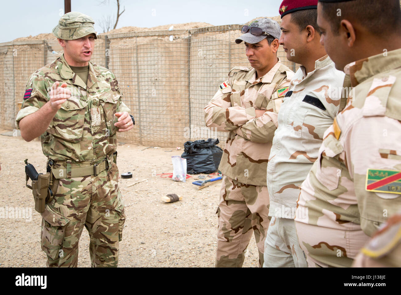 A British army explosive ordinance disposal soldier, deployed in support of Combined Joint Task Force – Operation Inherent Resolve and assigned to 2nd Battalion, Duke of Lancaster Regiment, gives Iraqi security forces soldiers a safety brief before configuring disruption charges during counter-improvised explosive device  training at Camp Taji, Iraq, April 9, 2017.   This training is part of the overall Combined Joint Task Force – Operation Inherent Resolve building partner capacity mission by training and improving the capability of partnered forces fighting ISIS. CJTF-OIR is the global Coali Stock Photo