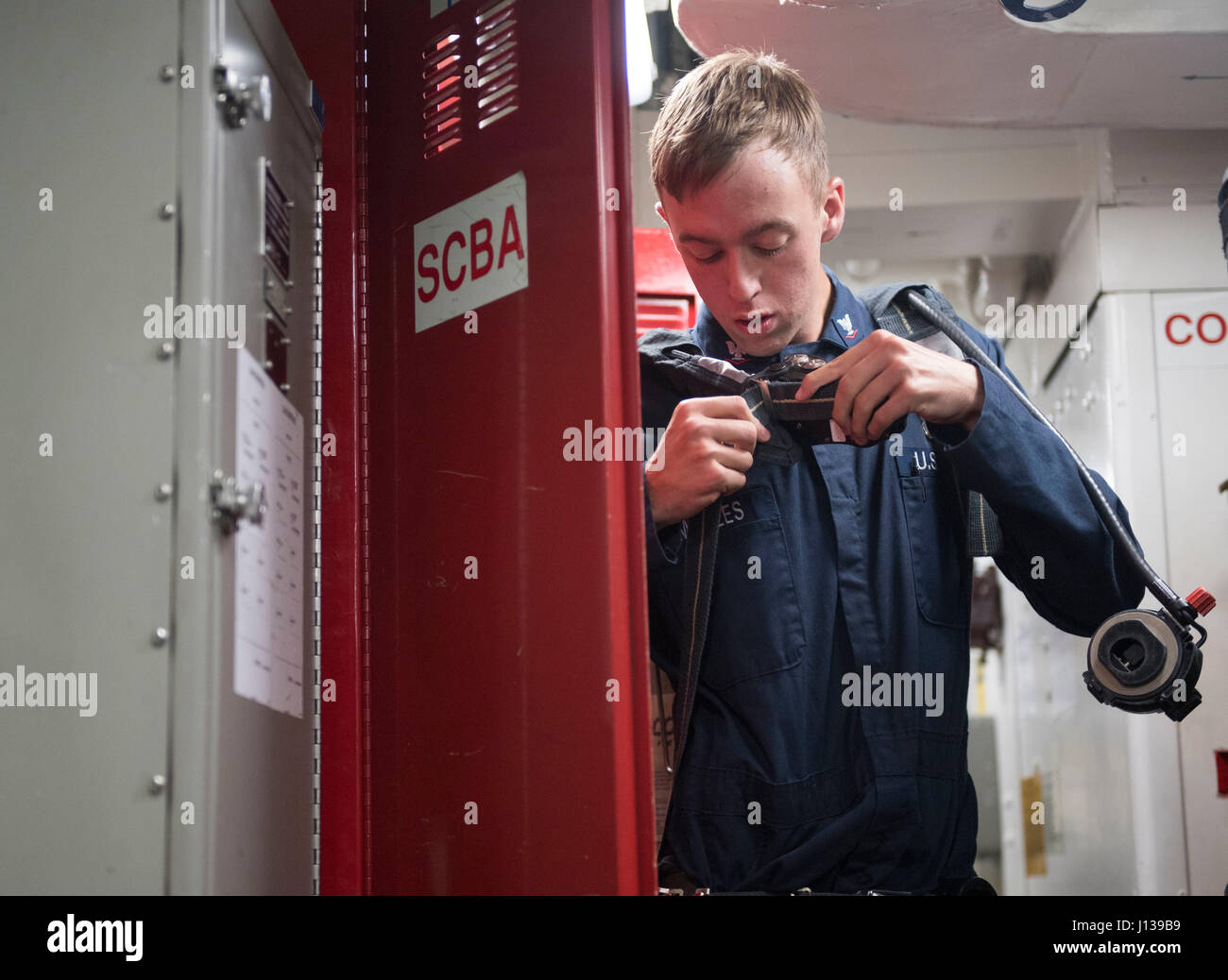170410-N-PP996-004 SOUTH CHINA SEA (April 10, 2017) Gas Turbine System Technician (Mechanical) 3rd Class Jesse Maples, from San Simone, Arizona, dons a self contained breathing apparatus during a damage control drill aboard Arleigh Burke-class guided-missile destroyer USS Michael Murphy (DDG 112). Michael Murphy is on a regularly scheduled Western Pacific deployment with the Carl Vinson Carrier Strike Group as part of the U.S. Pacific Fleet-led initiative to extend the command and control functions of U.S. 3rd Fleet. U.S. Navy aircraft carrier strike groups have patrolled the Indo-Asia-Pacific Stock Photo