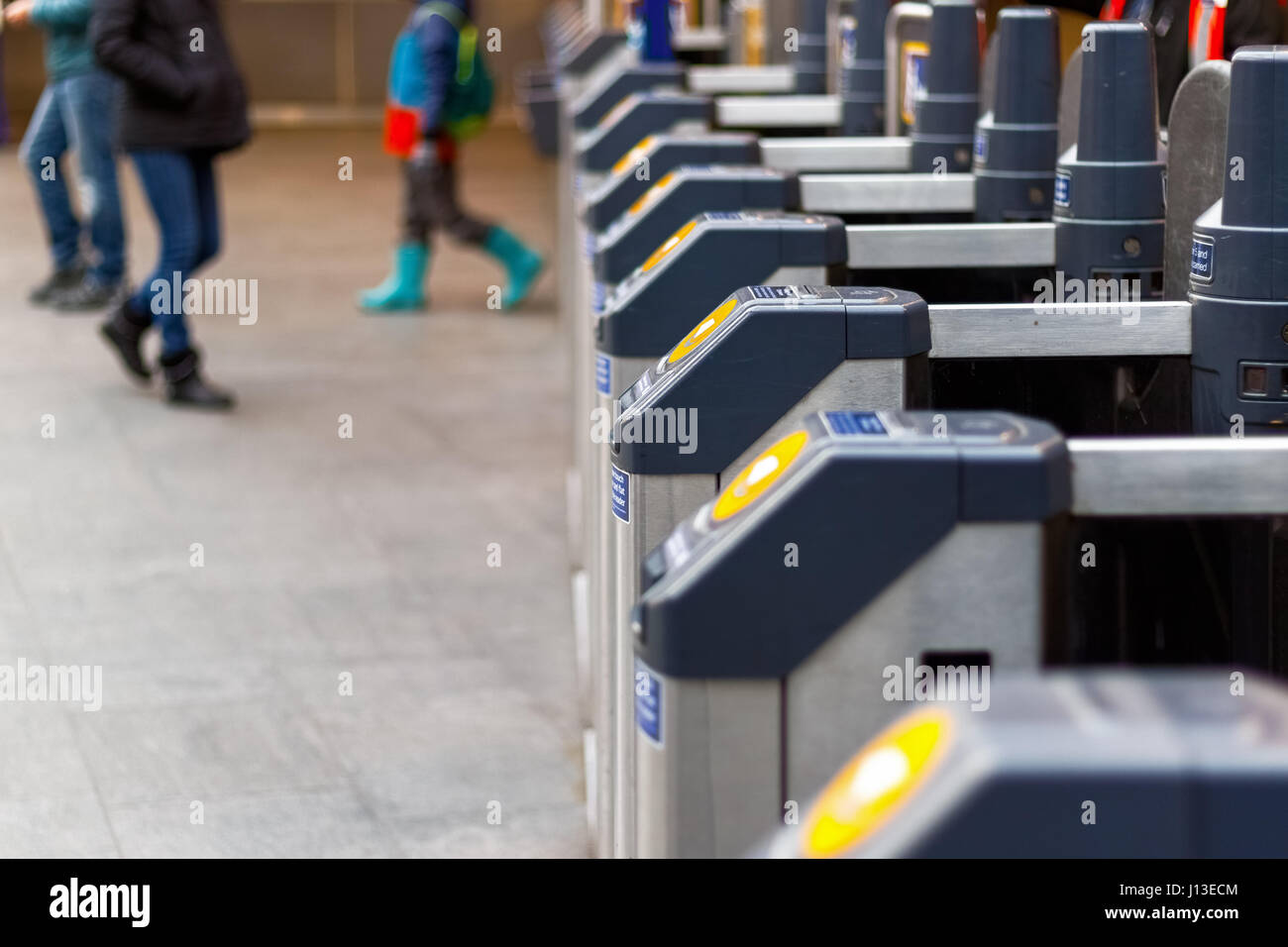 London, UK - February 28, 2017 - Ticket barrier at King's Cross station with people walking in the background Stock Photo