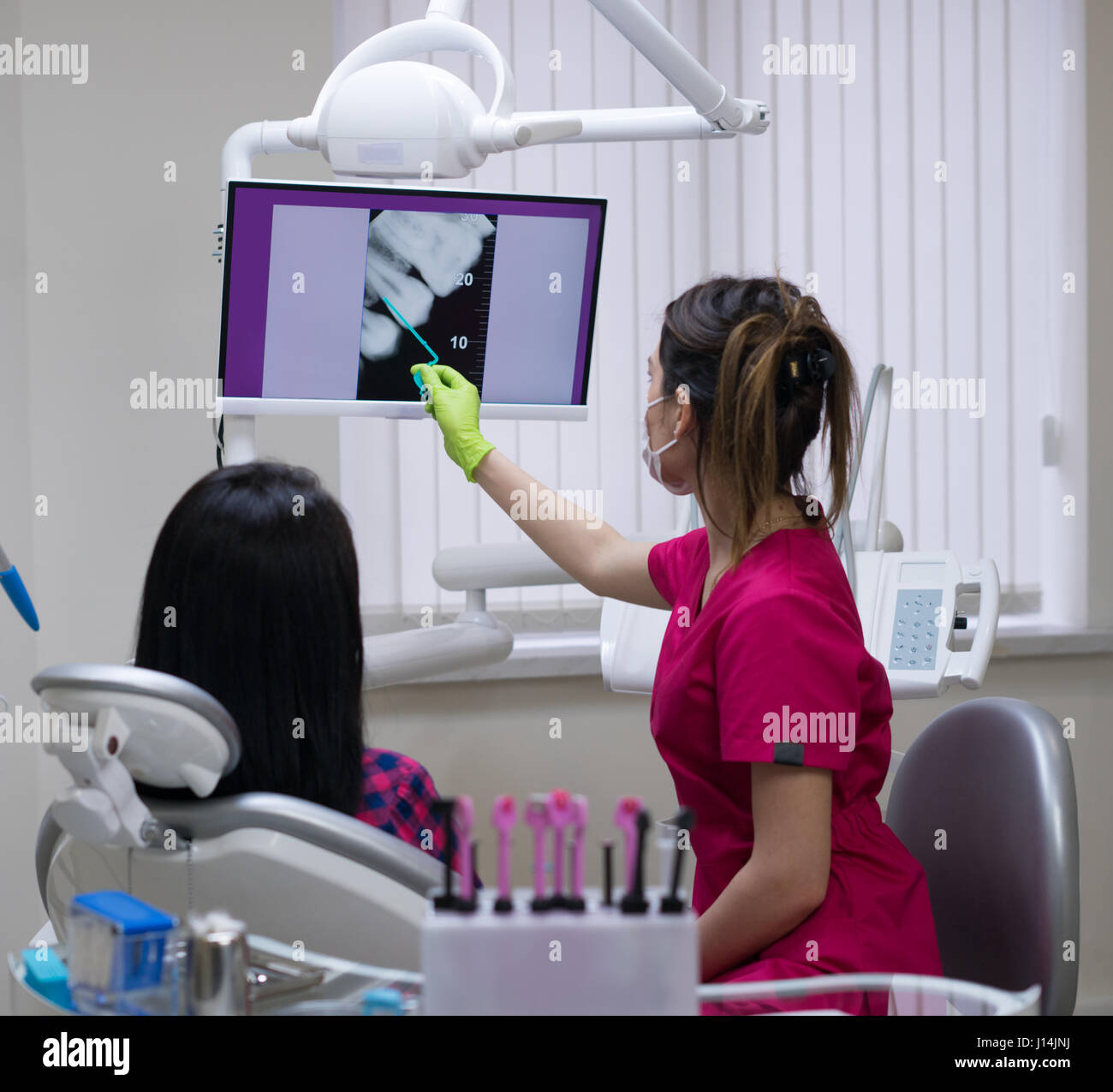 Dentist Showing Tooth X Ray Image For Woman Patient In Dental Clinic On A Big Screen Dentist Showing Tooth X Ray Image For Woman Patient In Dental Clinic On A Big Screen