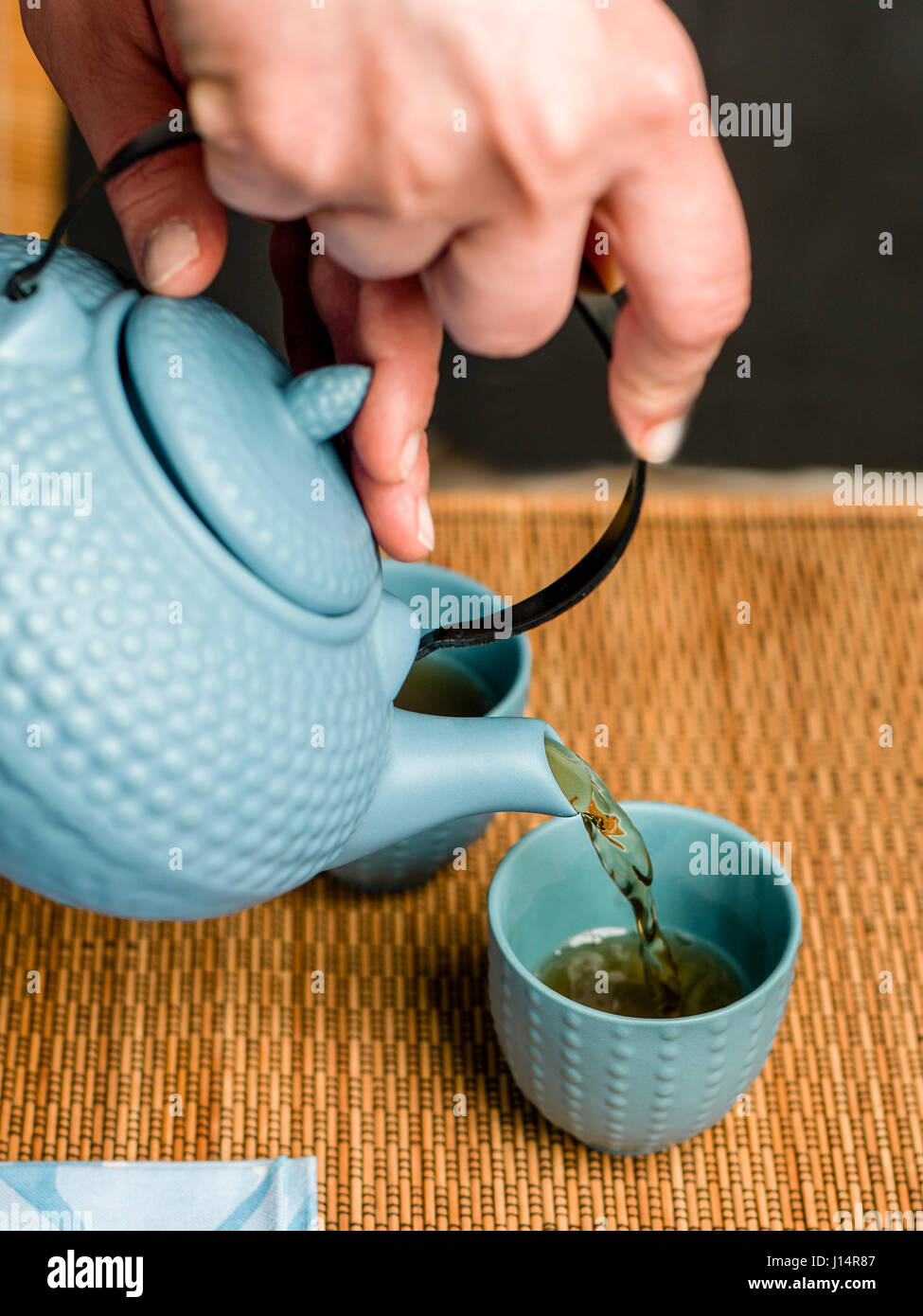 Woman delicately pouring tea from an asian style teapot Japanese tea